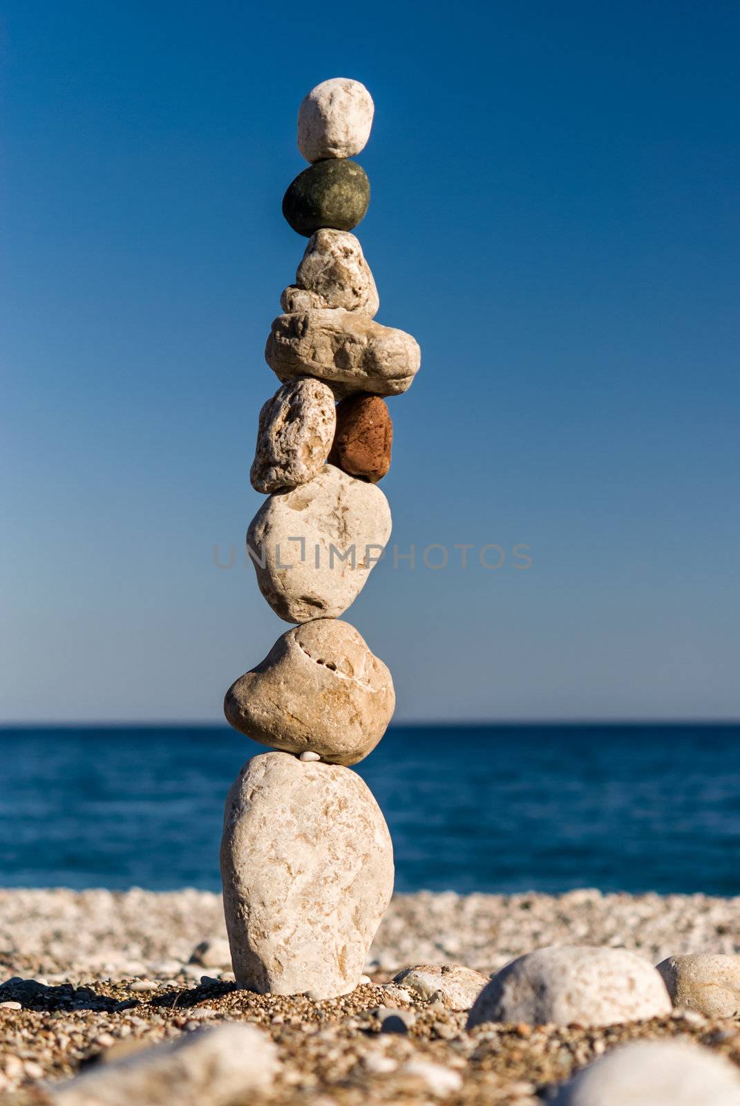 Stones staked in tower on the beach by kirs-ua