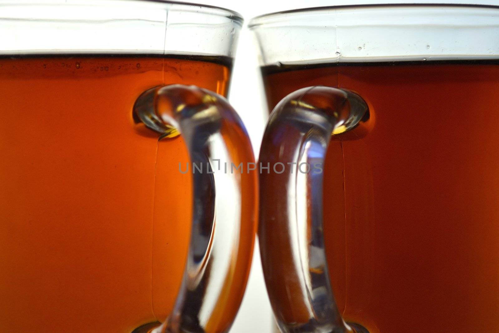 Two glass cups of tea over white background