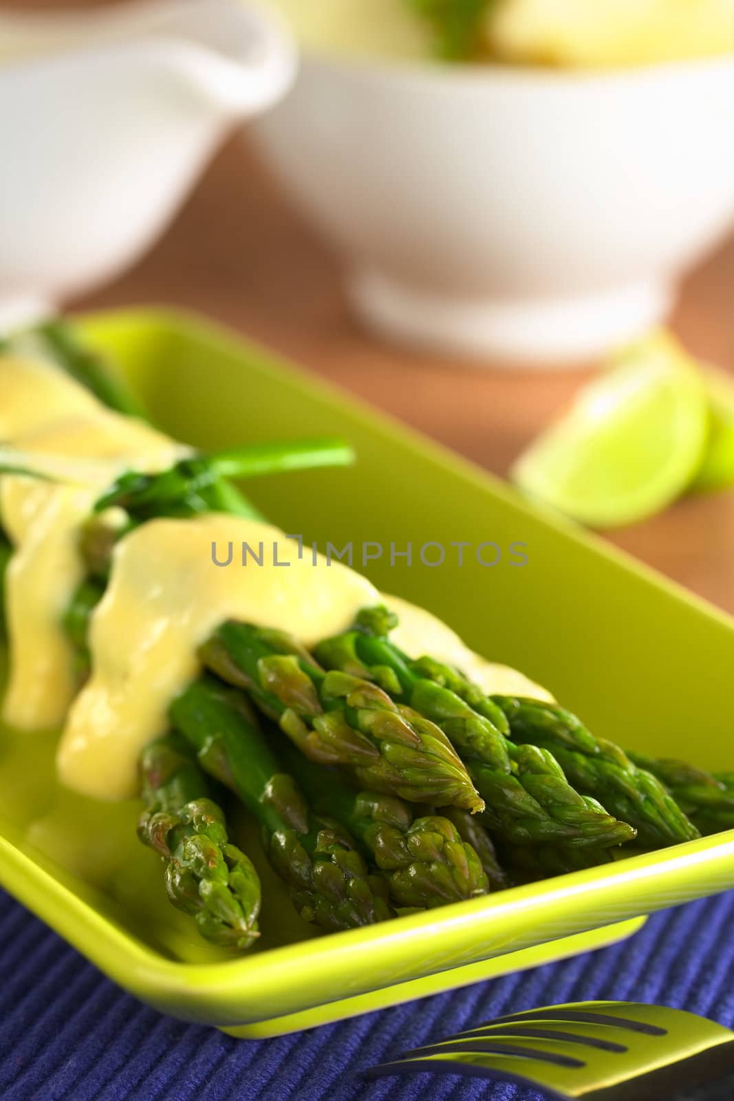 Cooked green asparagus with Hollandaise sauce on top (Selective Focus, Focus on the asparagus tip on the top)