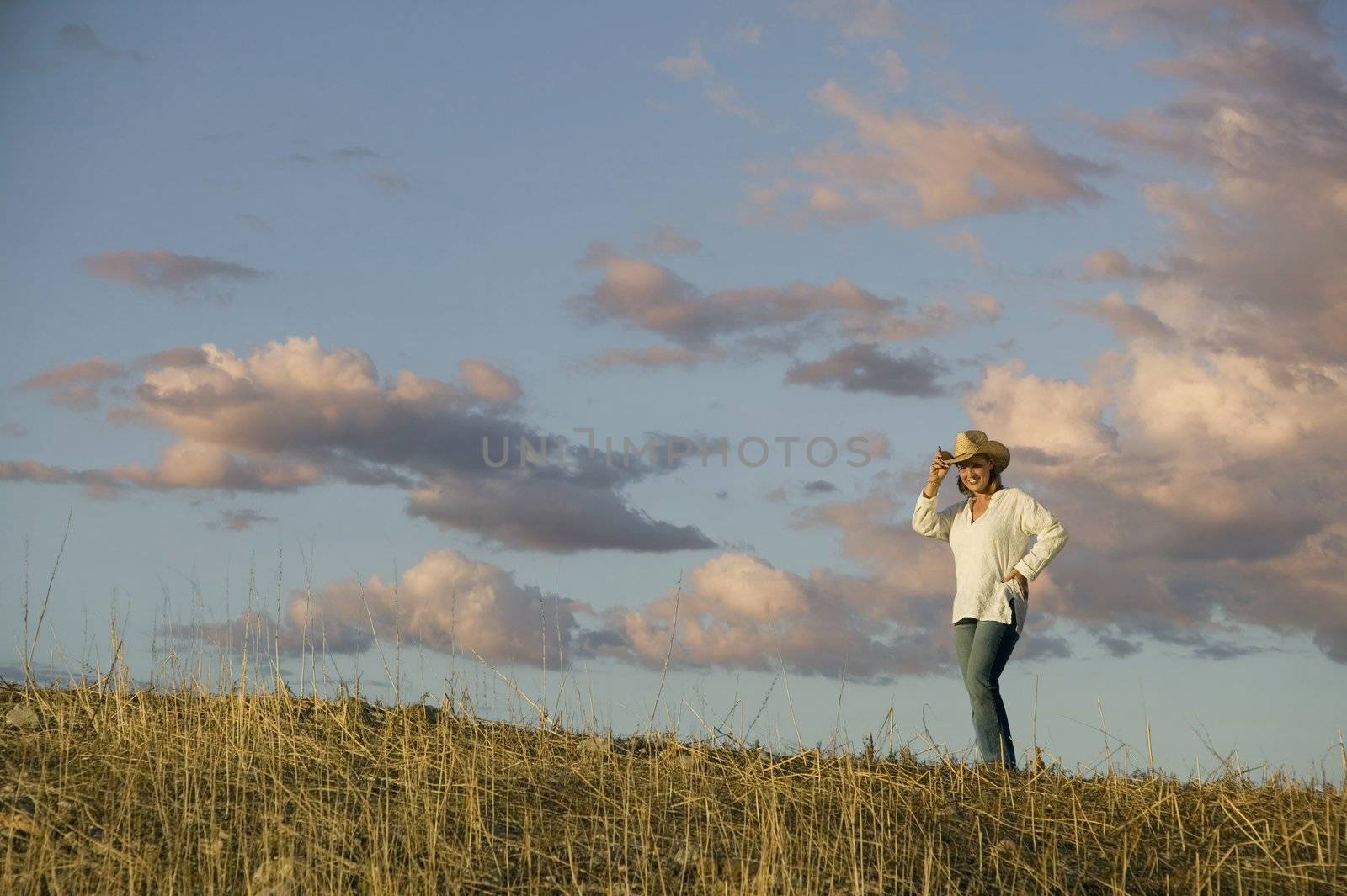 Wide angle shot of a western woman against a cloudy sky at dusk.