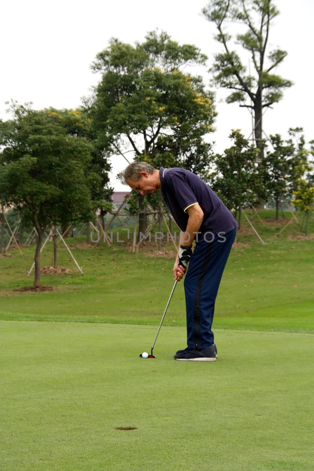 a retired golfer lining up a putt