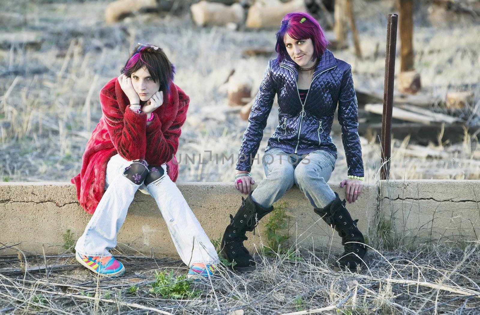 Two Fashion Girls Sitting on a Cement wall
