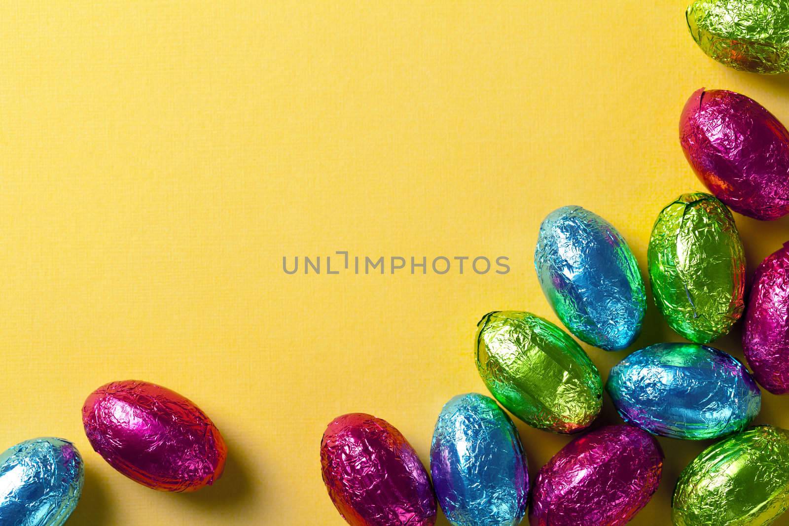 Chocolate easter eggs on yellow paper background. Top view, macro shot