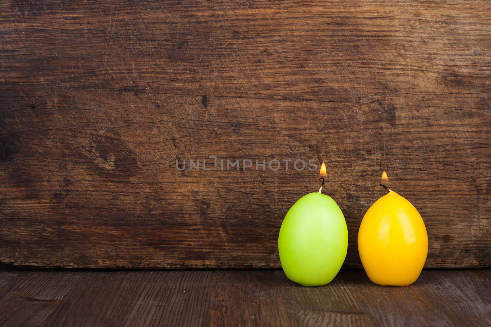 Candles in the form of eggs on the background of a wooden surface