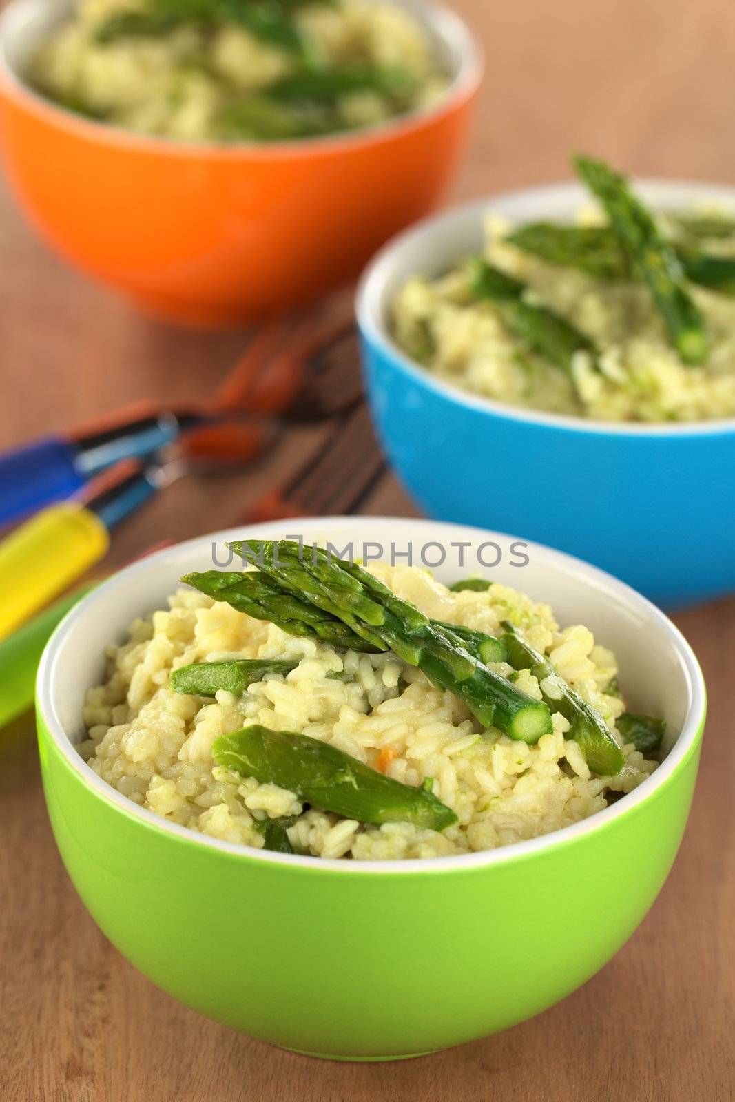 Green asparagus risotto in colorful bowls (Selective Focus, Focus on the two asparagus tips on the first risotto)