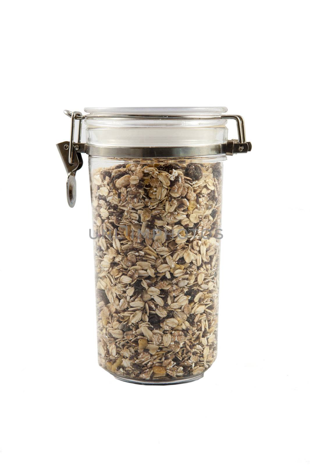 A transparent jar full of oats, fruits and nuts.