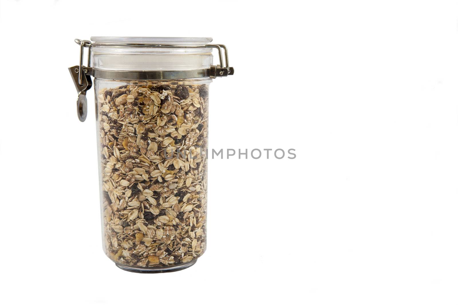 A transparent jar full of oats, fruits and nuts.