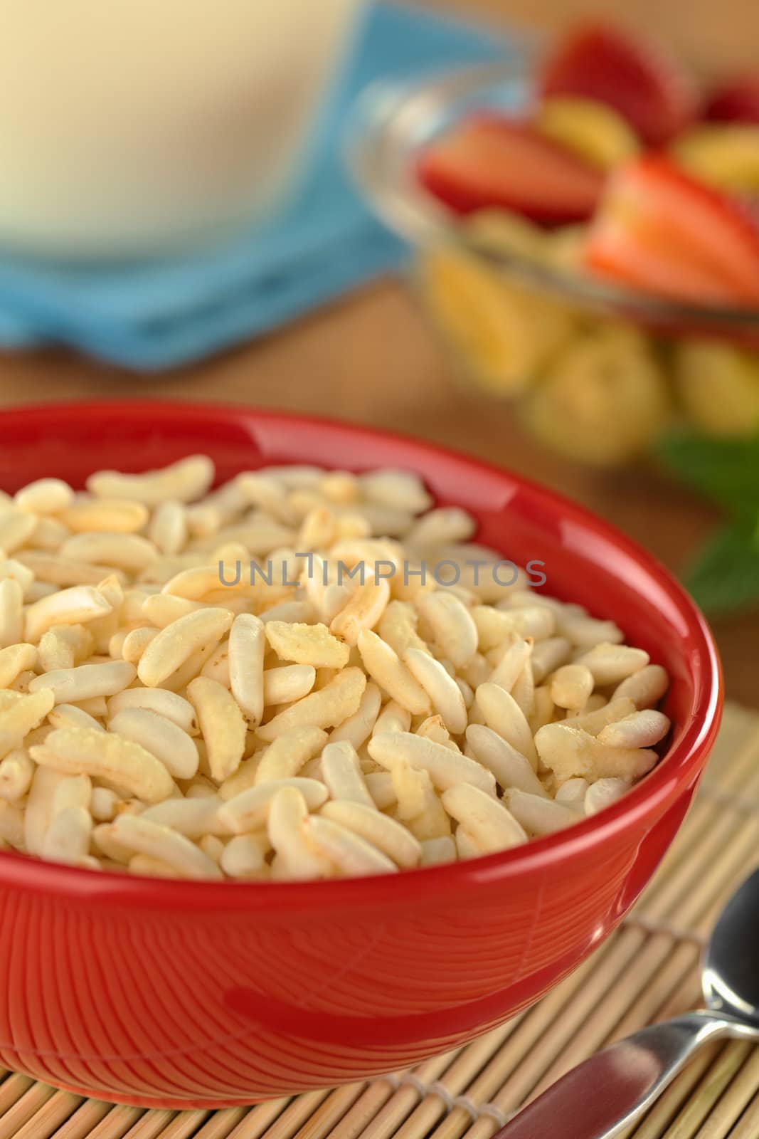 Puffed rice cereal with fruits and milk in the back (Selective Focus, Focus in the middle of the bowl)