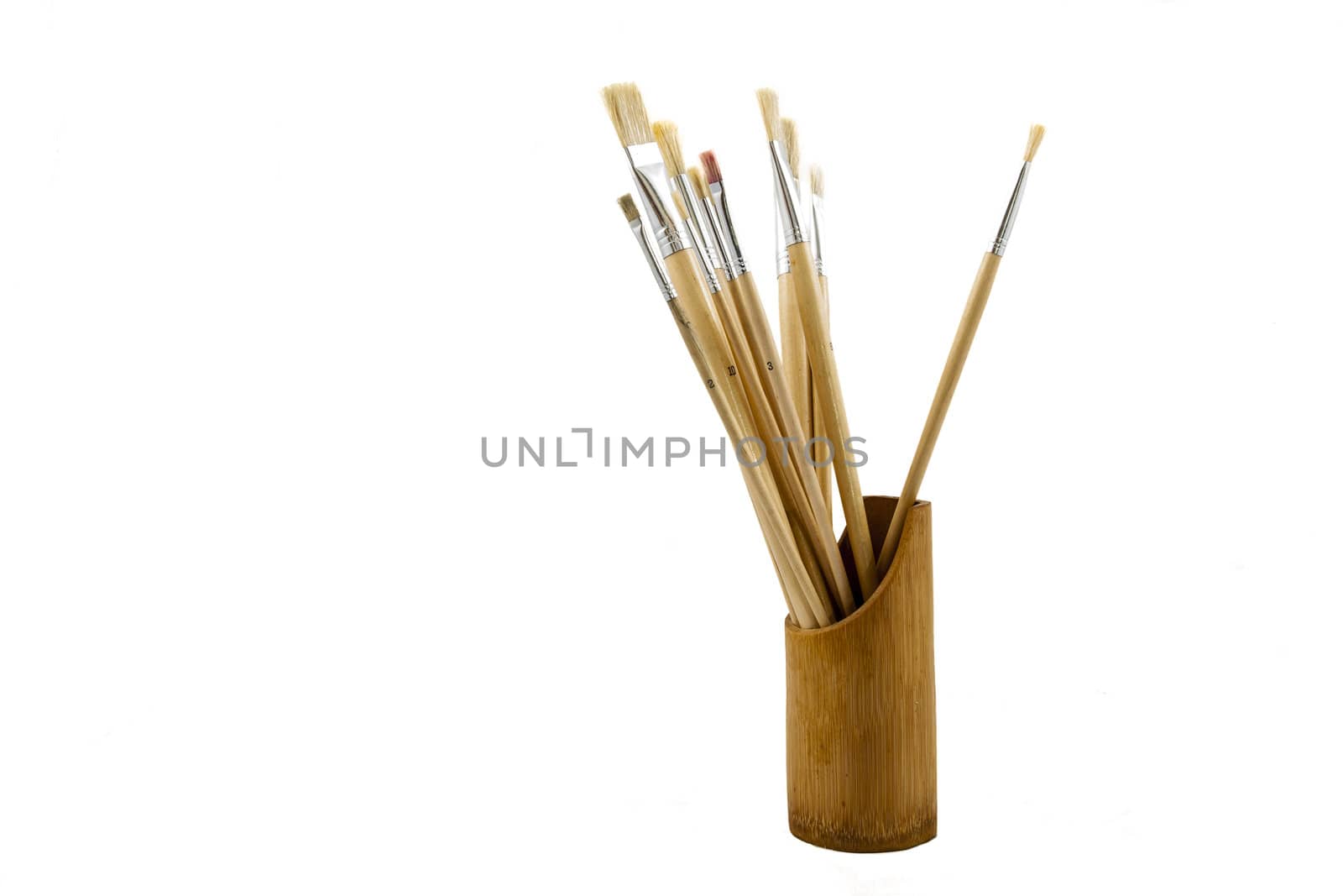 Artistic painting brushes in wooden pot over white backdrop