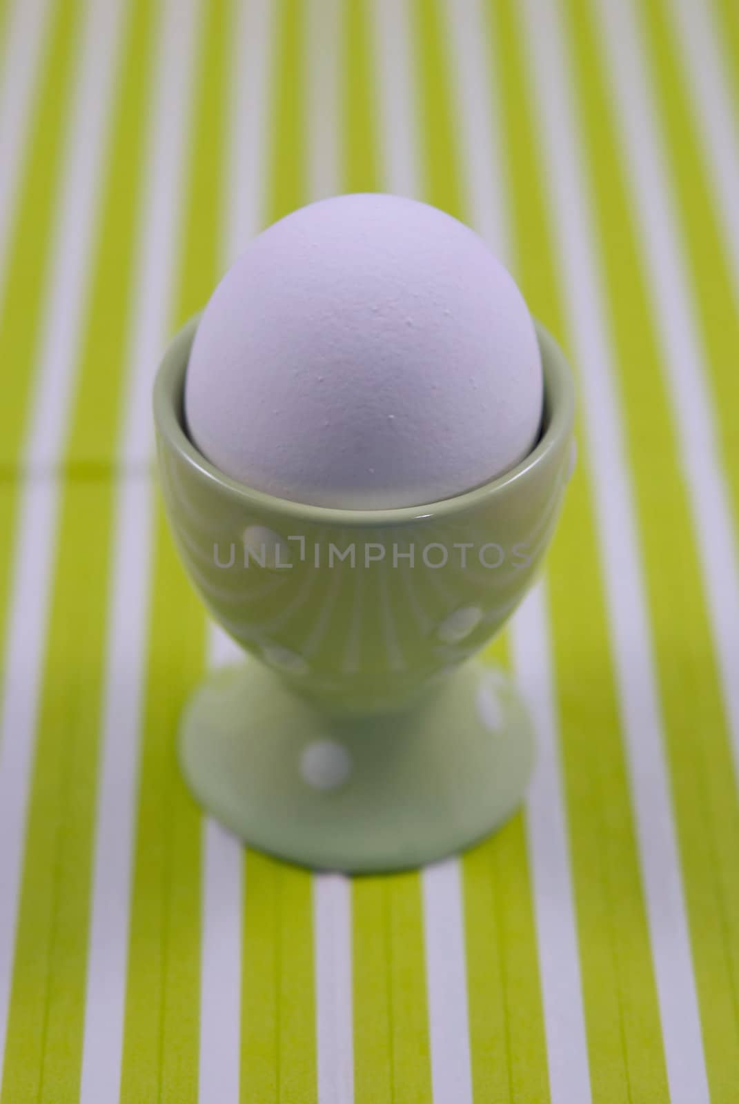 White breakfast egg in the egg cups on the green and white striped background