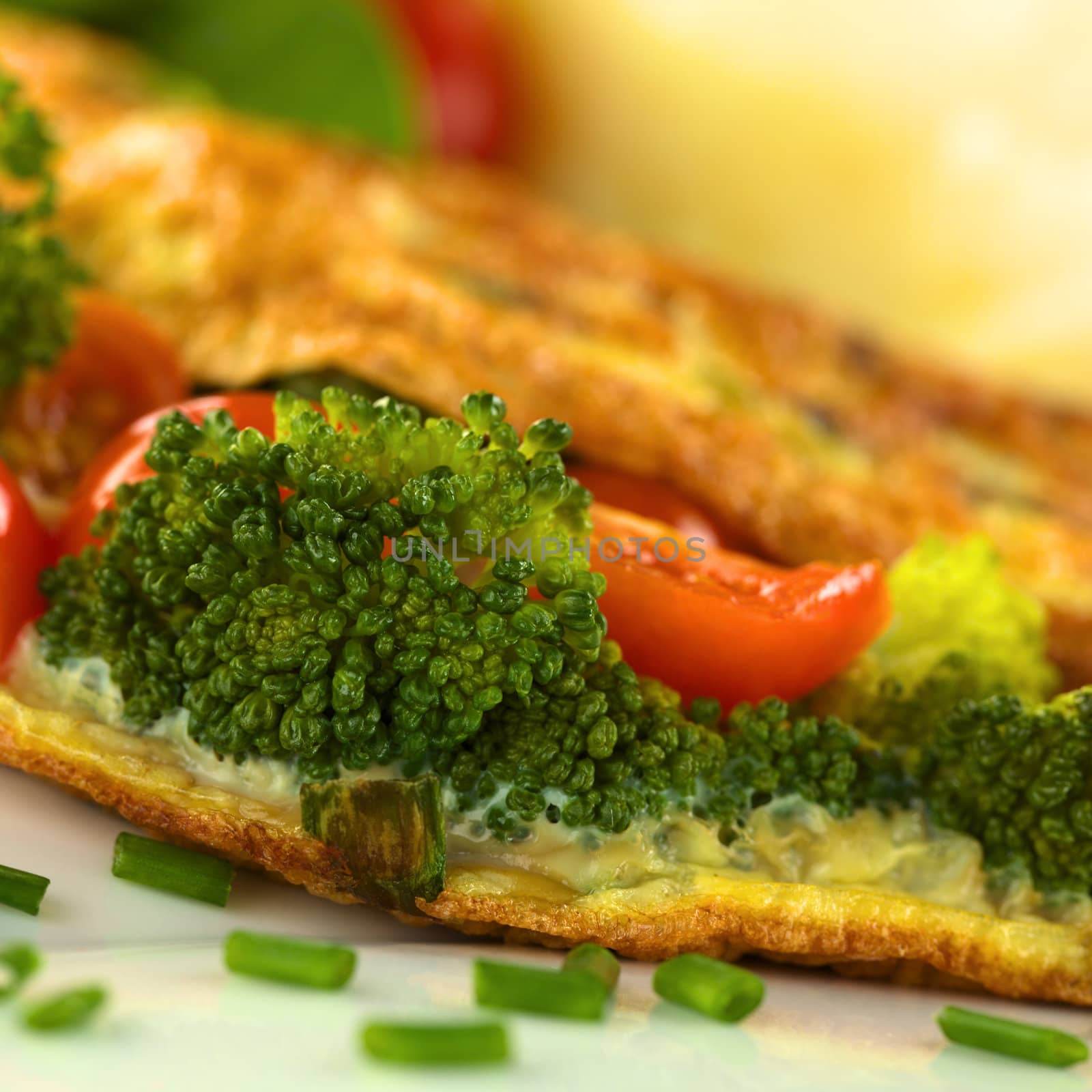 Broccoli and tomato omelette with mashed potato in the back (Selective Focus, Focus on the broccoli floret on the left)