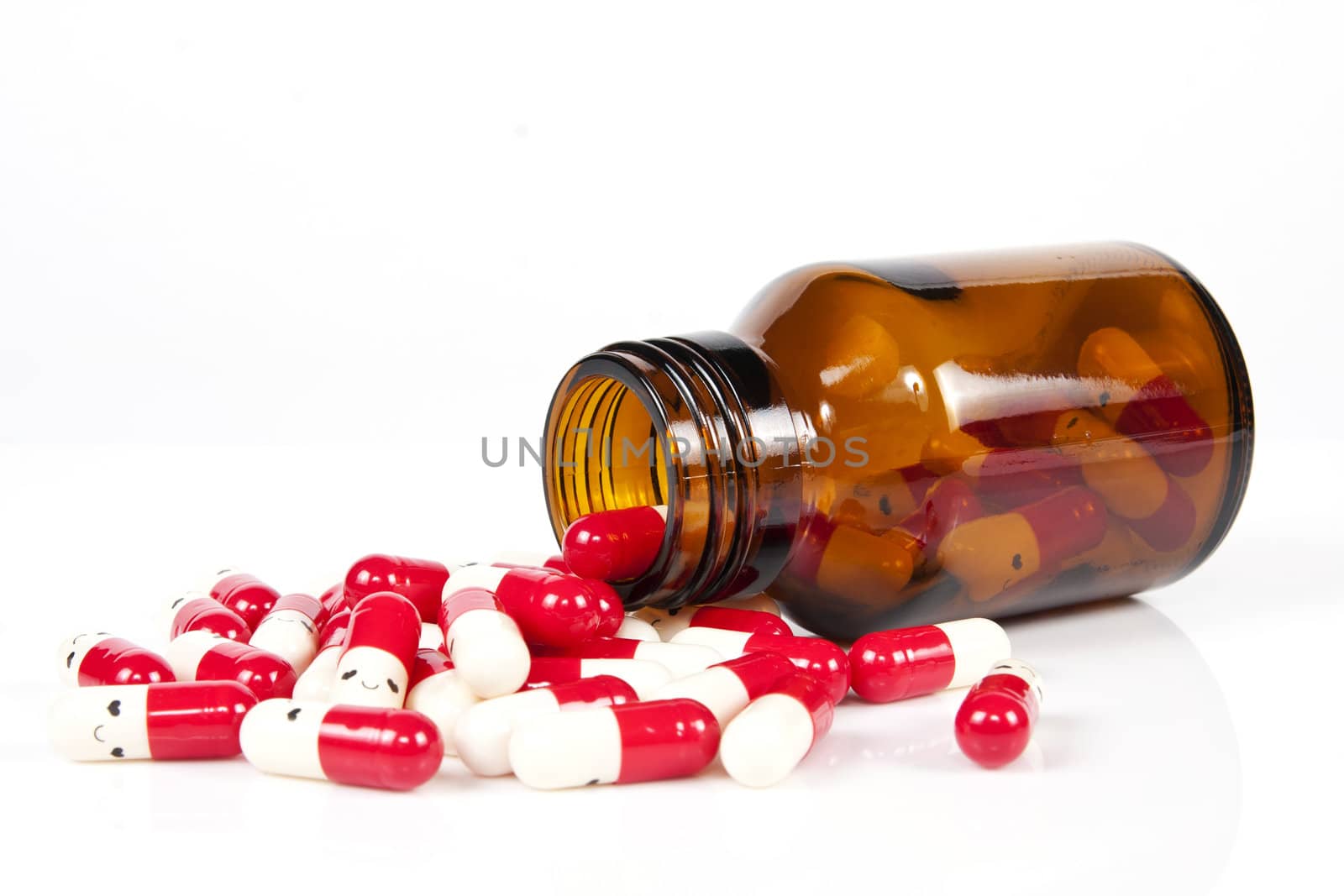 Open happy pill bottle with medicine spilling out of it isolated on white