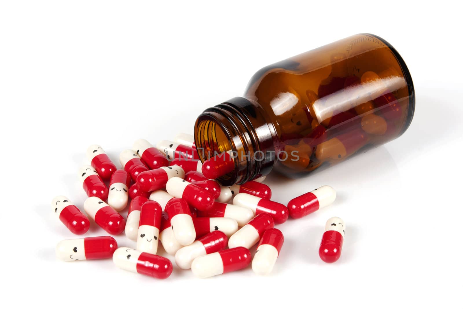 Open happy pill bottle with medicine spilling out of it isolated on white
