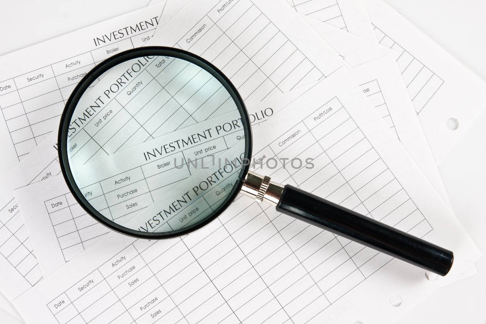 Close up stack of investment Spreadsheets and Magnifying Glass