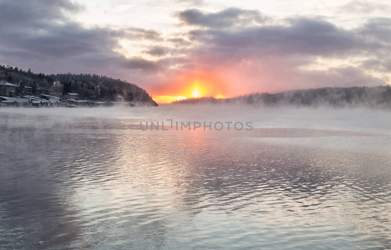 Frosty mist over the lake with the setting sun