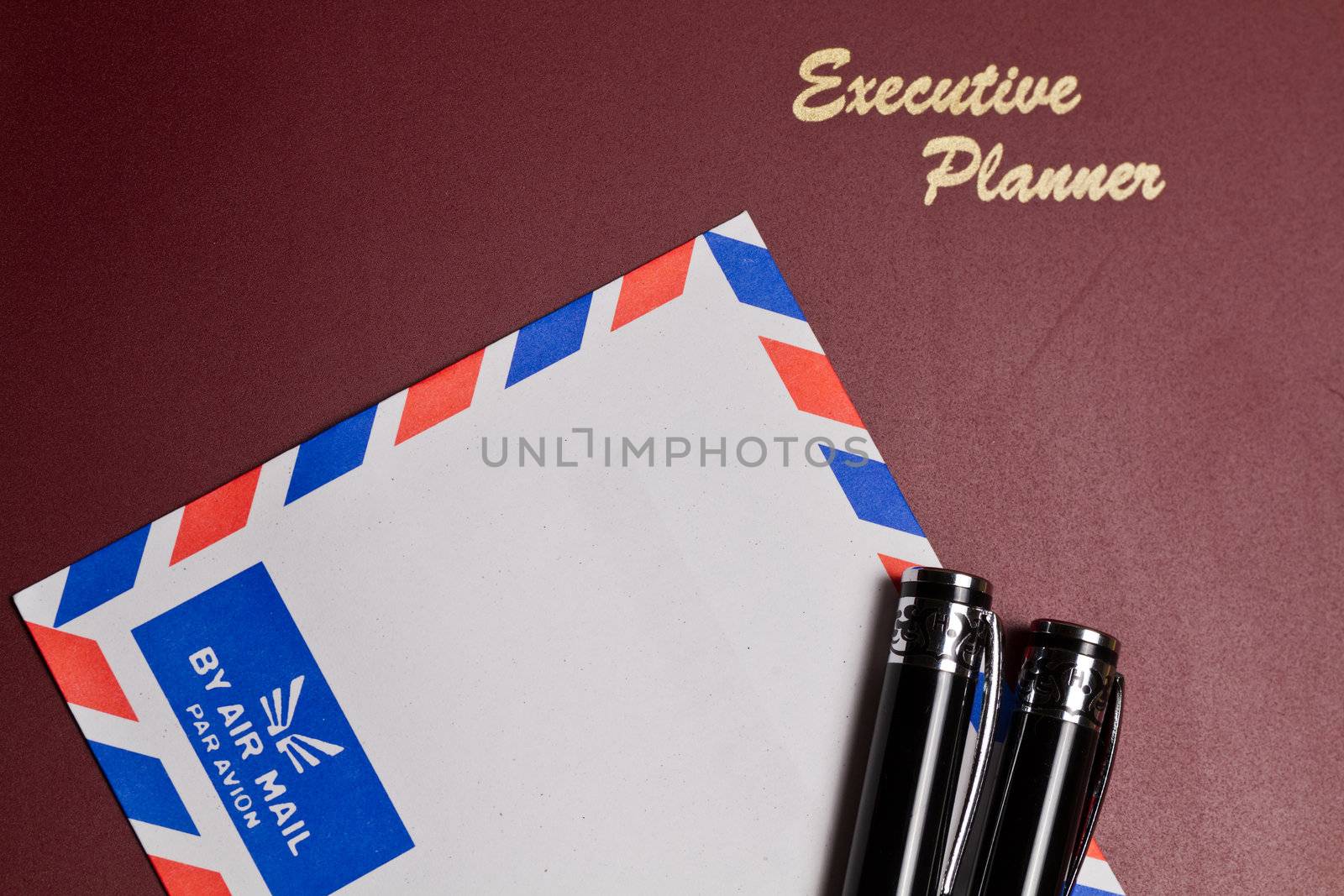 executive planner with white by air mail envelopw and pens  in landscape orientation