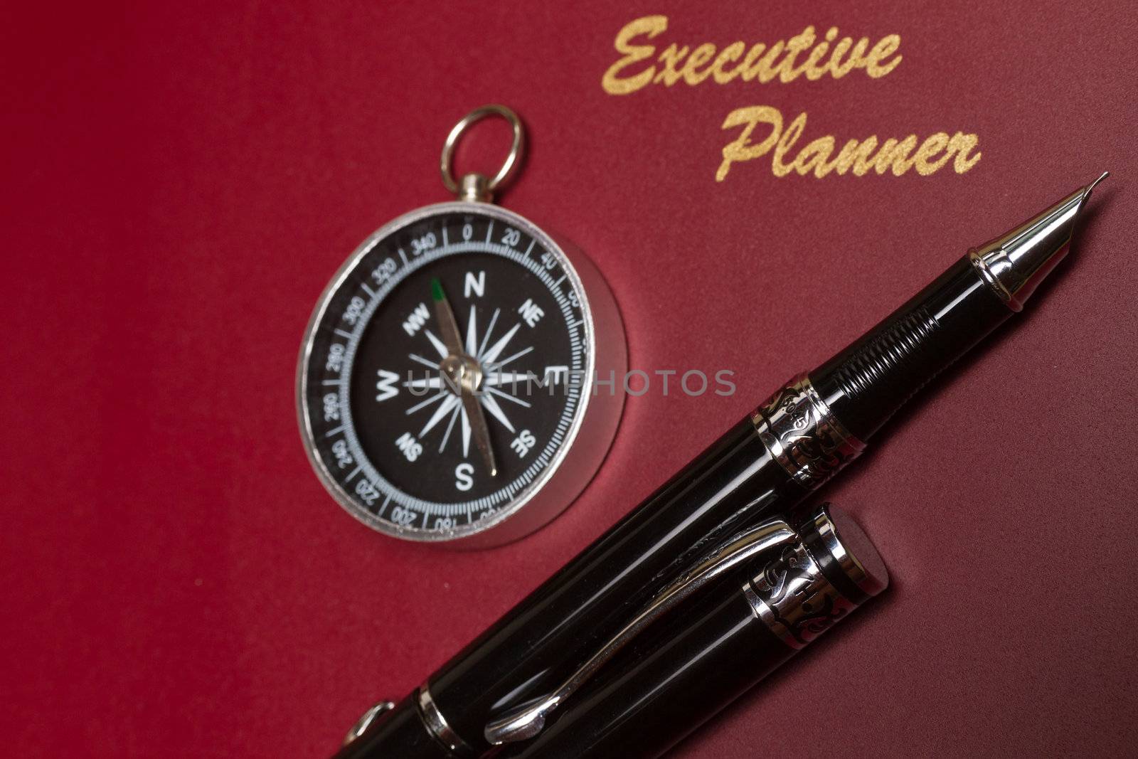 angled view of a dark red executive planner with simple compass and pens