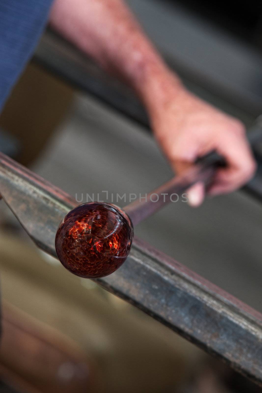 Rolling fine art glass vase cooling on iron workbench