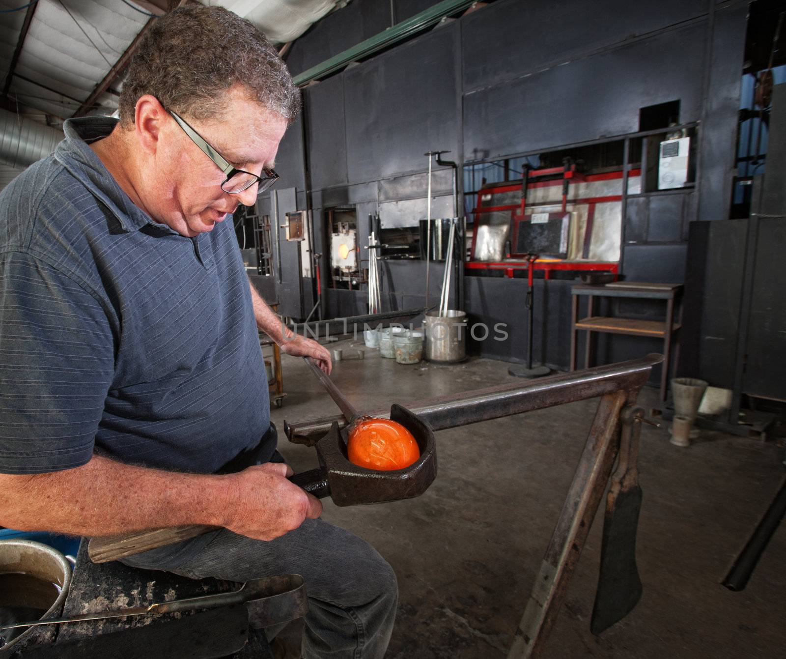 Middle aged glass worker clamping a round vase