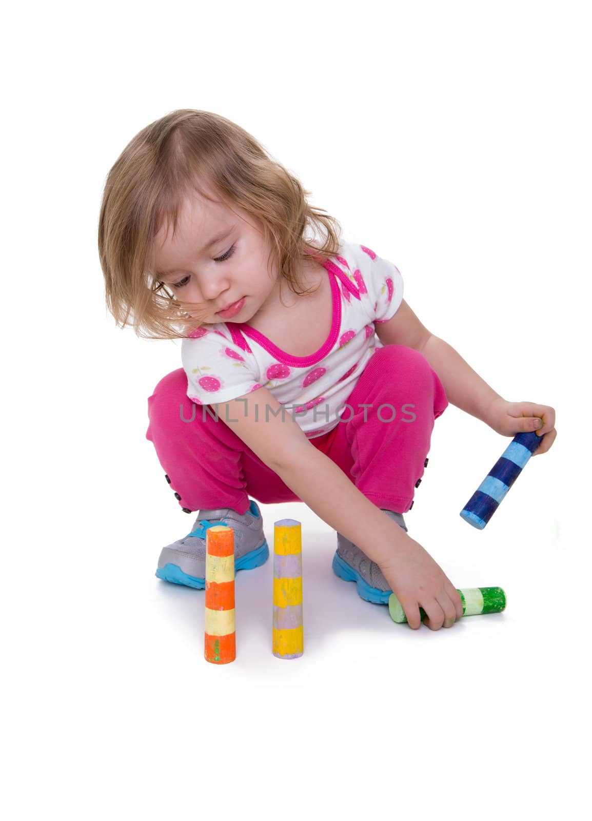 Toddler learning skills by paying attention to colorful crayons. Isolated on white with copy space.