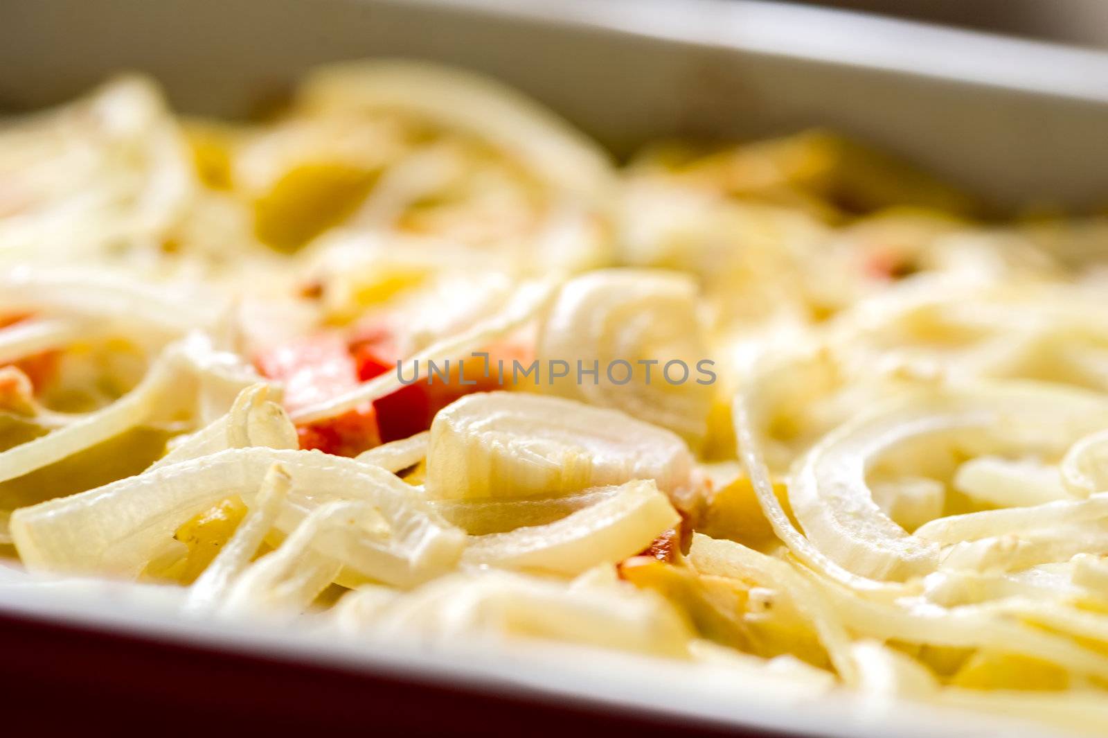 Close-up of baked in oven potatoes with onion served in the white casserole