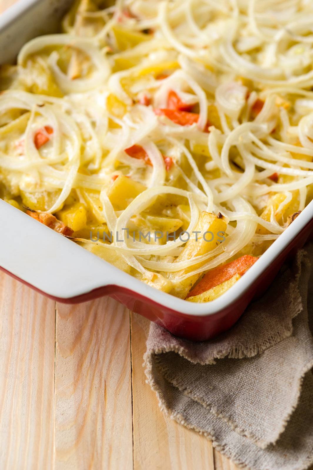 Close-up of baked in oven potatoes with onion served in the white casserole