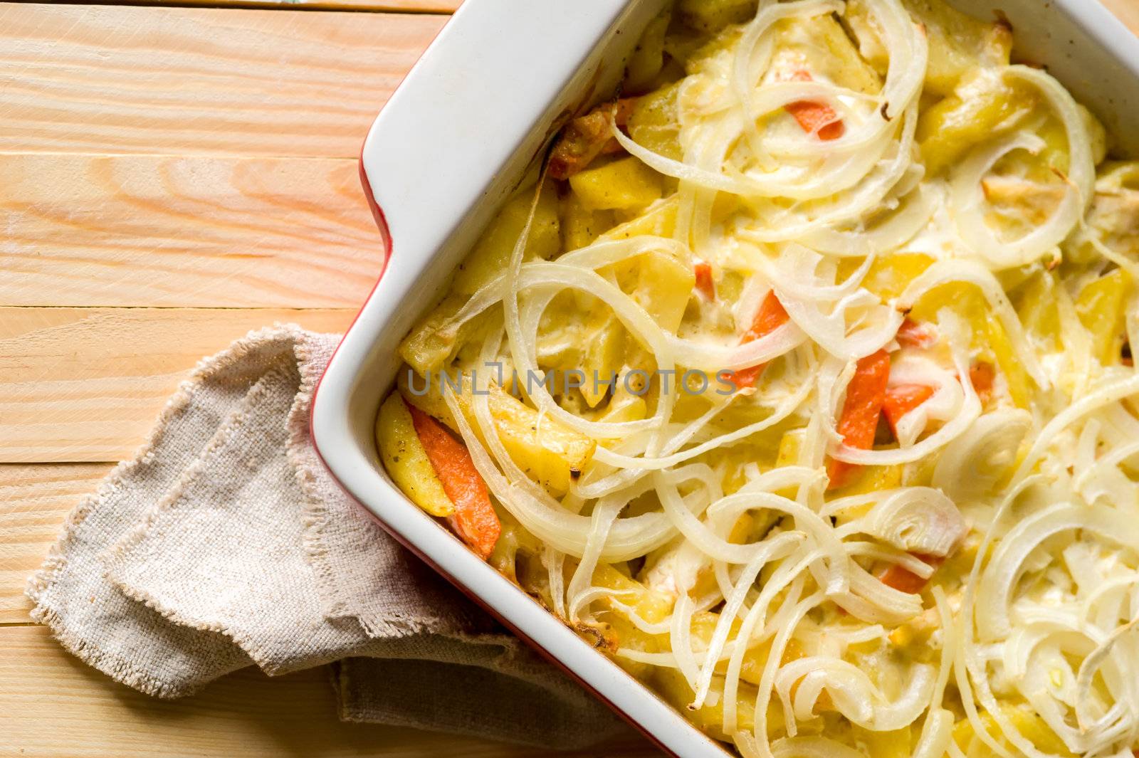 Close-up of baked in oven potatoes with onion served in the white casserole