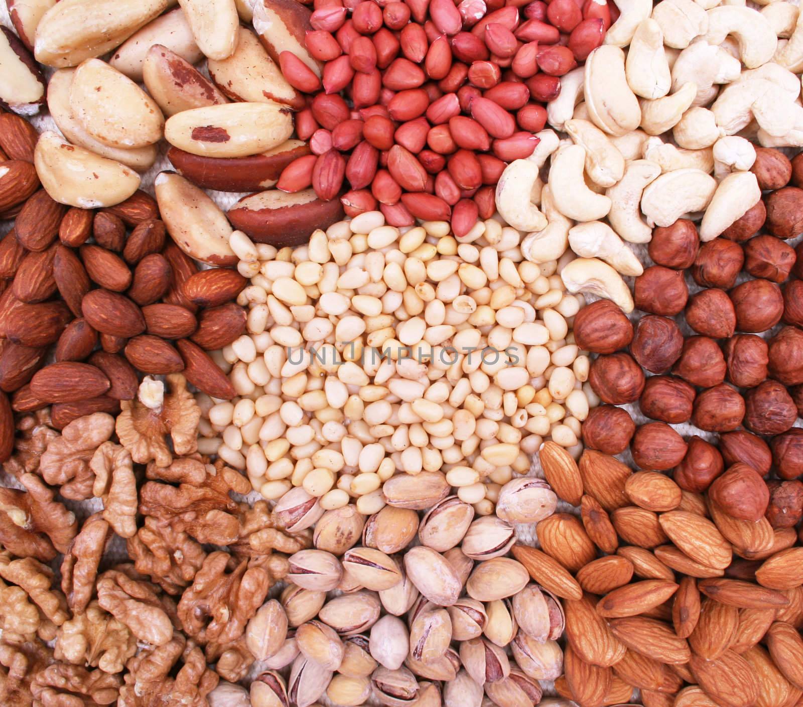 Assorted pine nuts, filbert, peanut, pistachios, walnut, almonds and  hazelnuts on natural sackcloth can use as background 
