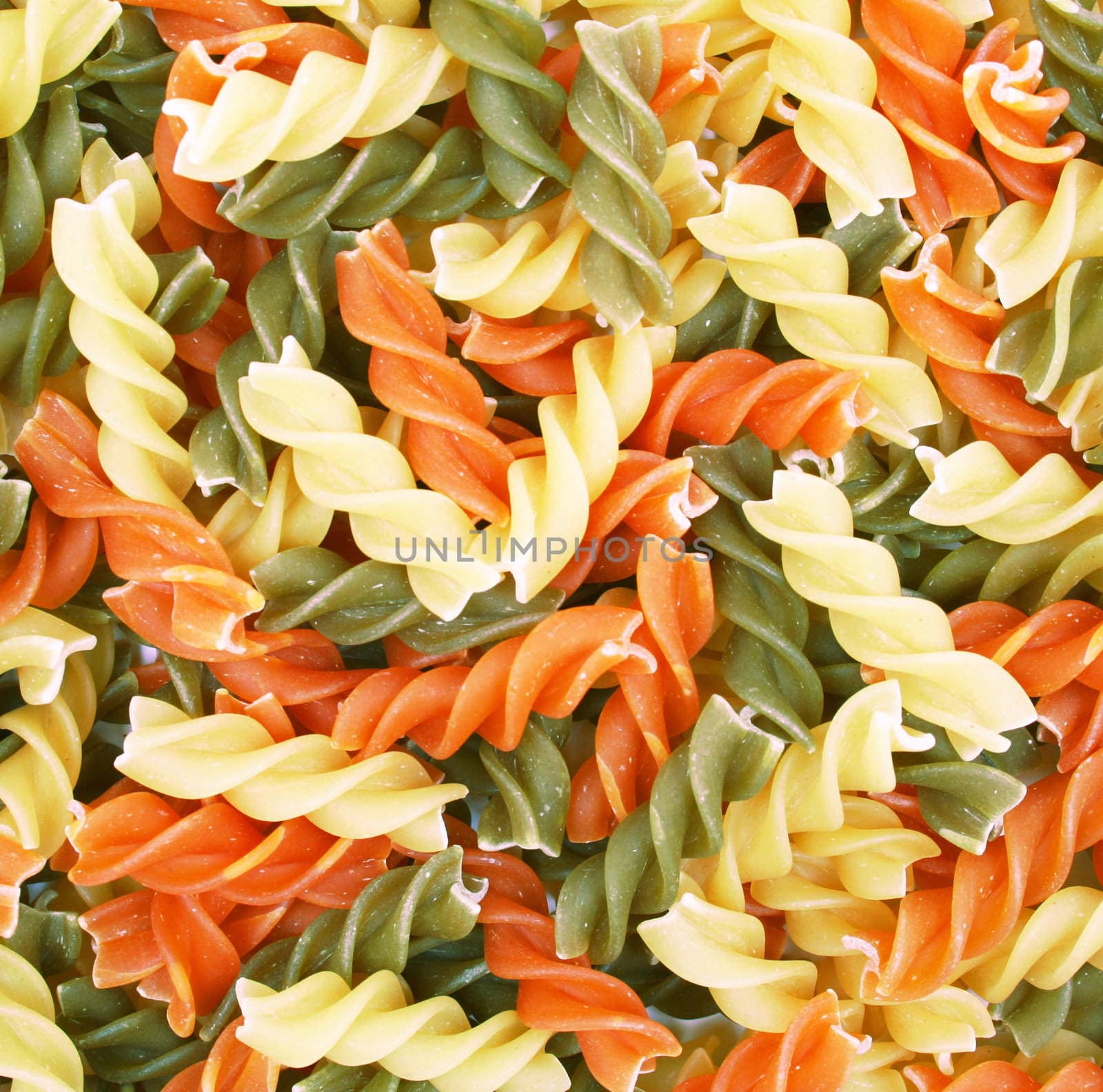 Uncooked italian pasta - three colors spirals as background