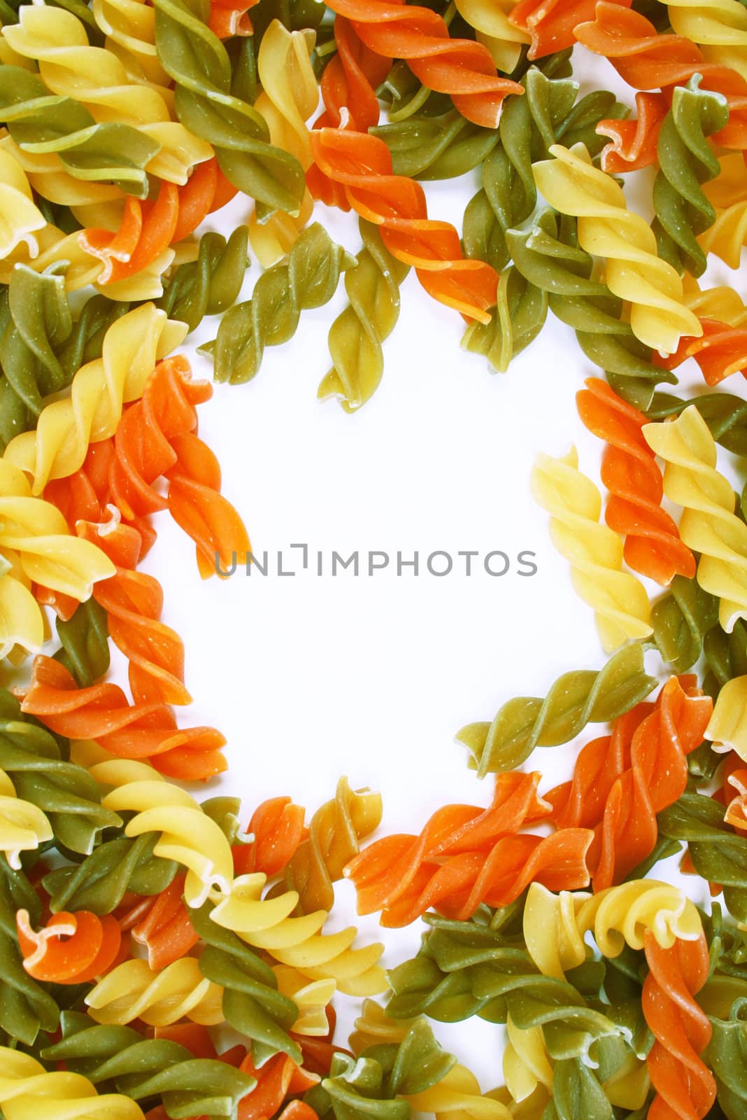 Uncooked italian pasta - three colors spirals as background