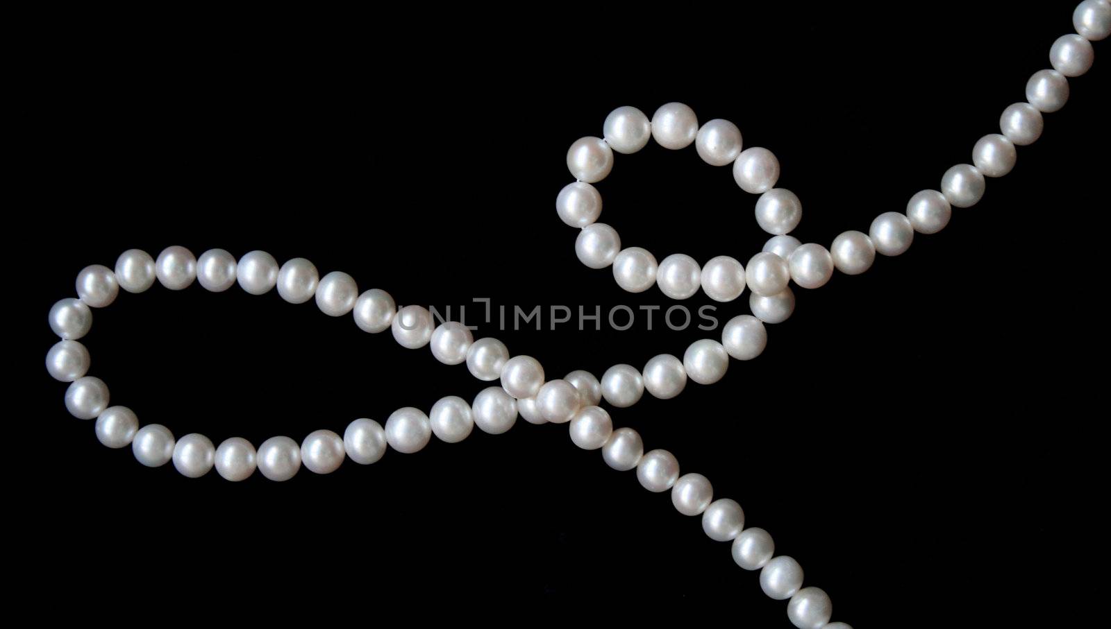 White pearls on the black velvet background 