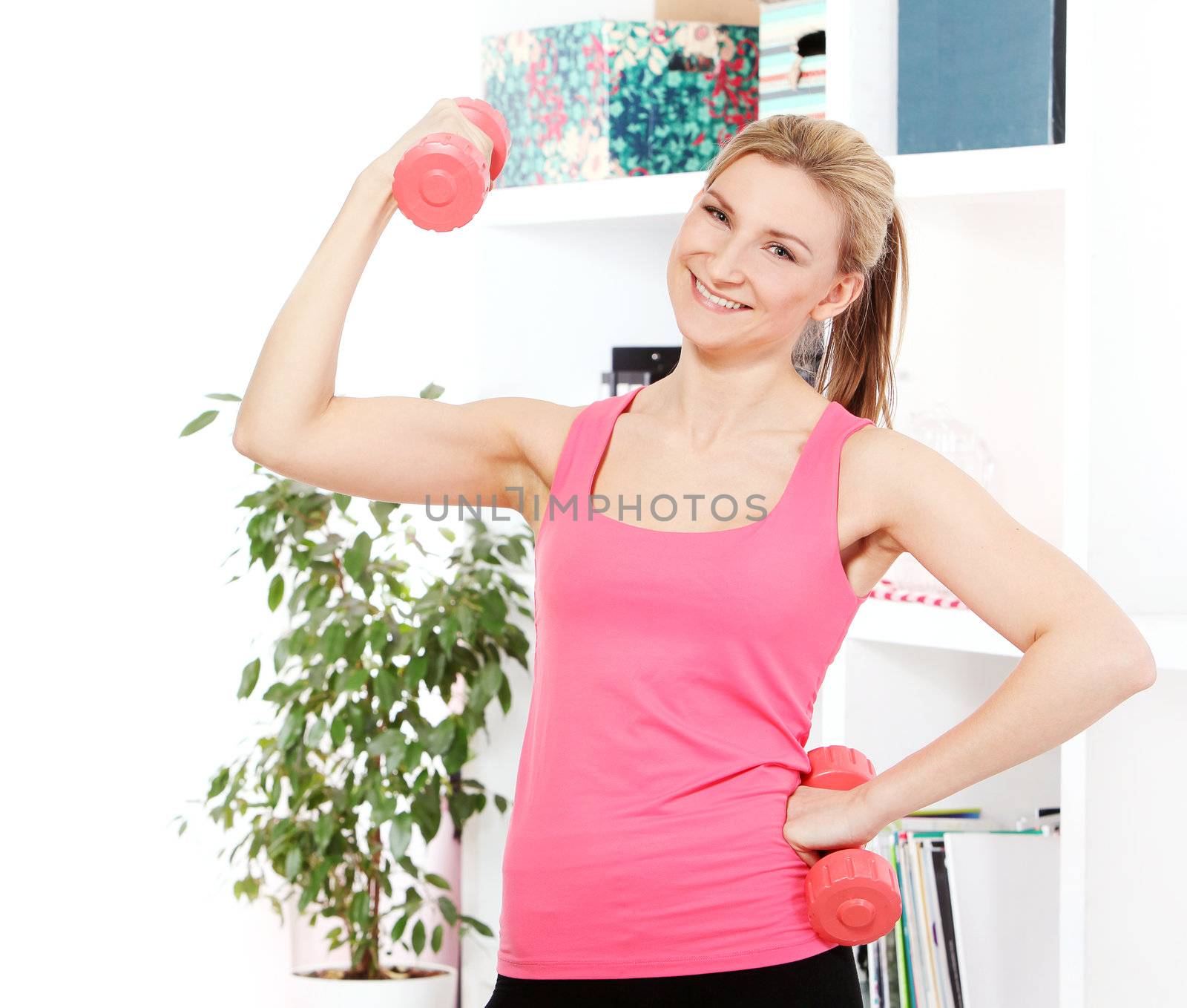 Young beautiful woman with dumbbells working out at home