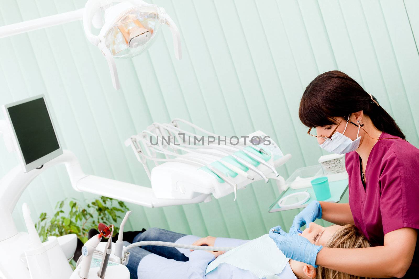Female dentist with mask and gloves working on patient