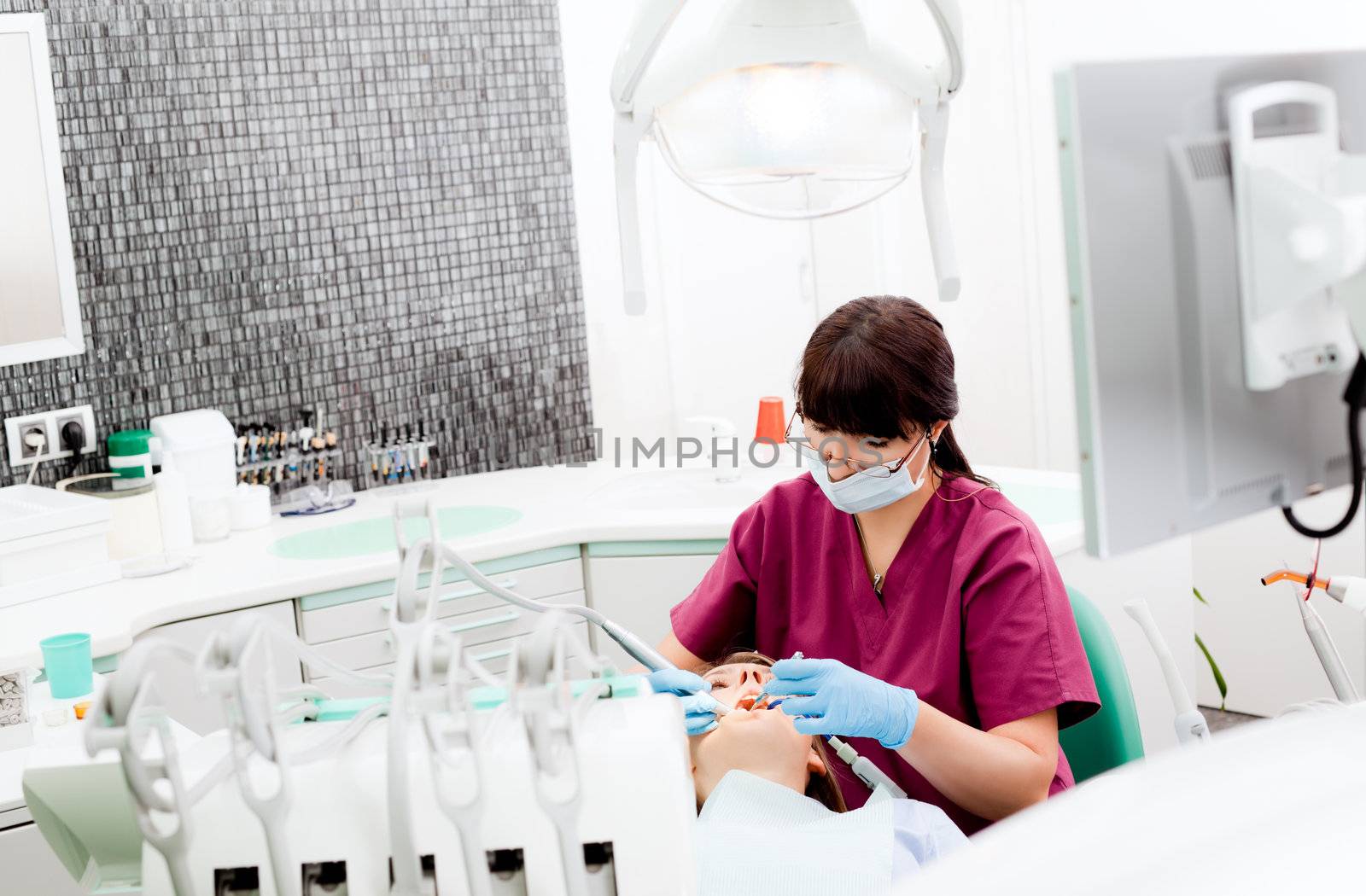 Female dentist working on patient in modern equipped cabinet