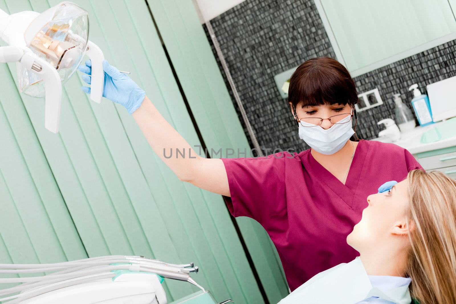 Female dentist with protective mask examining patient