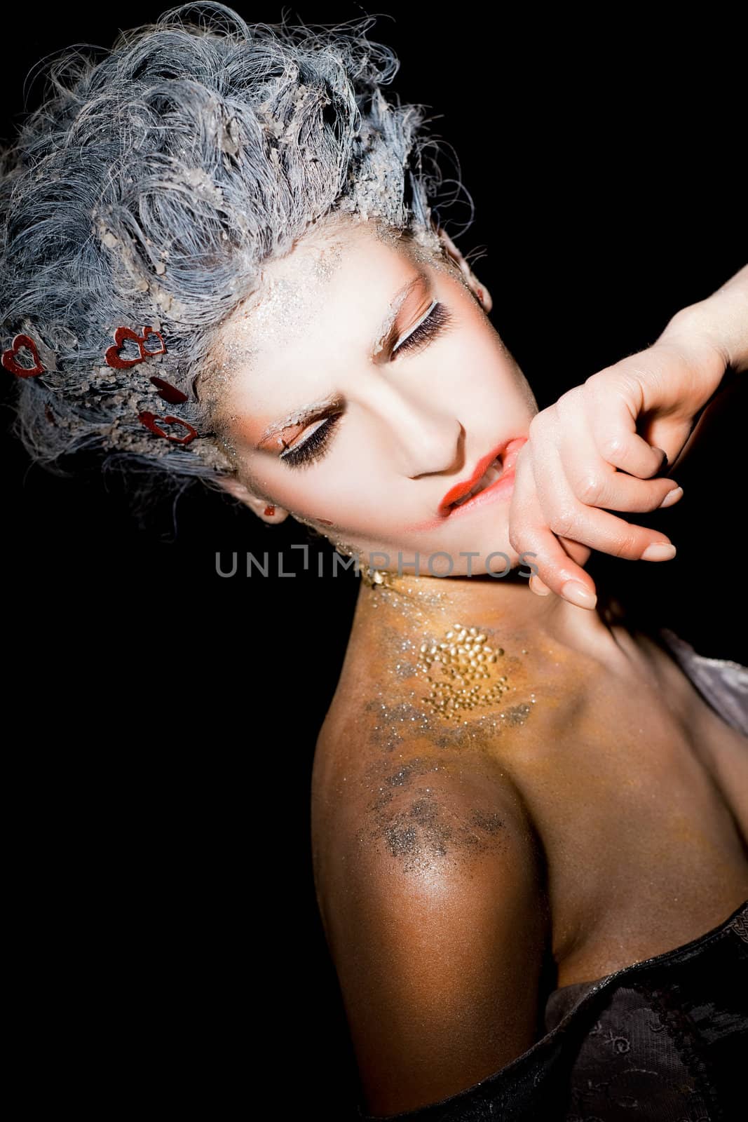 Portrait of woman with makeup, smudging her lipstick on black background