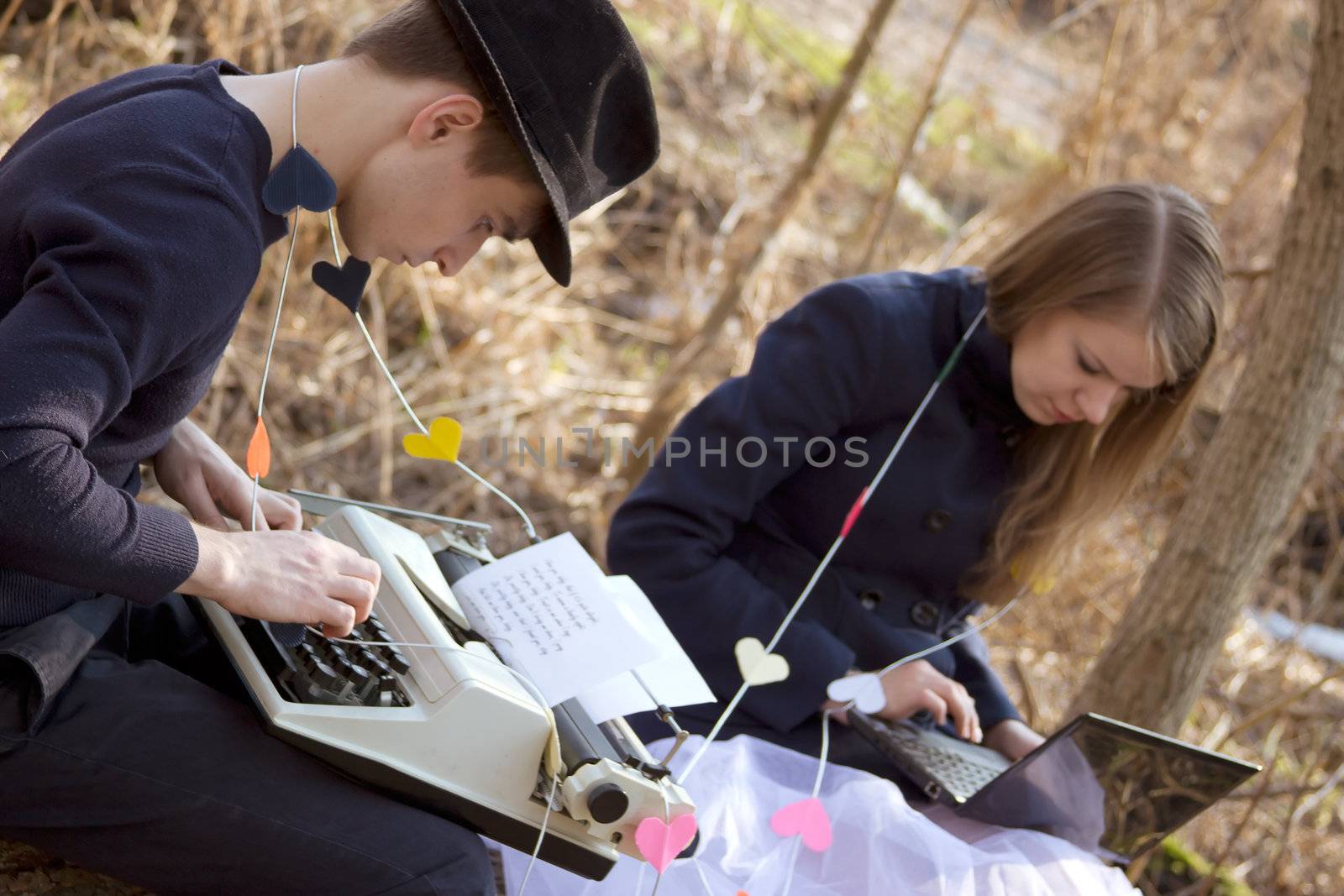 young man and woman typing on a typewriter in the park
