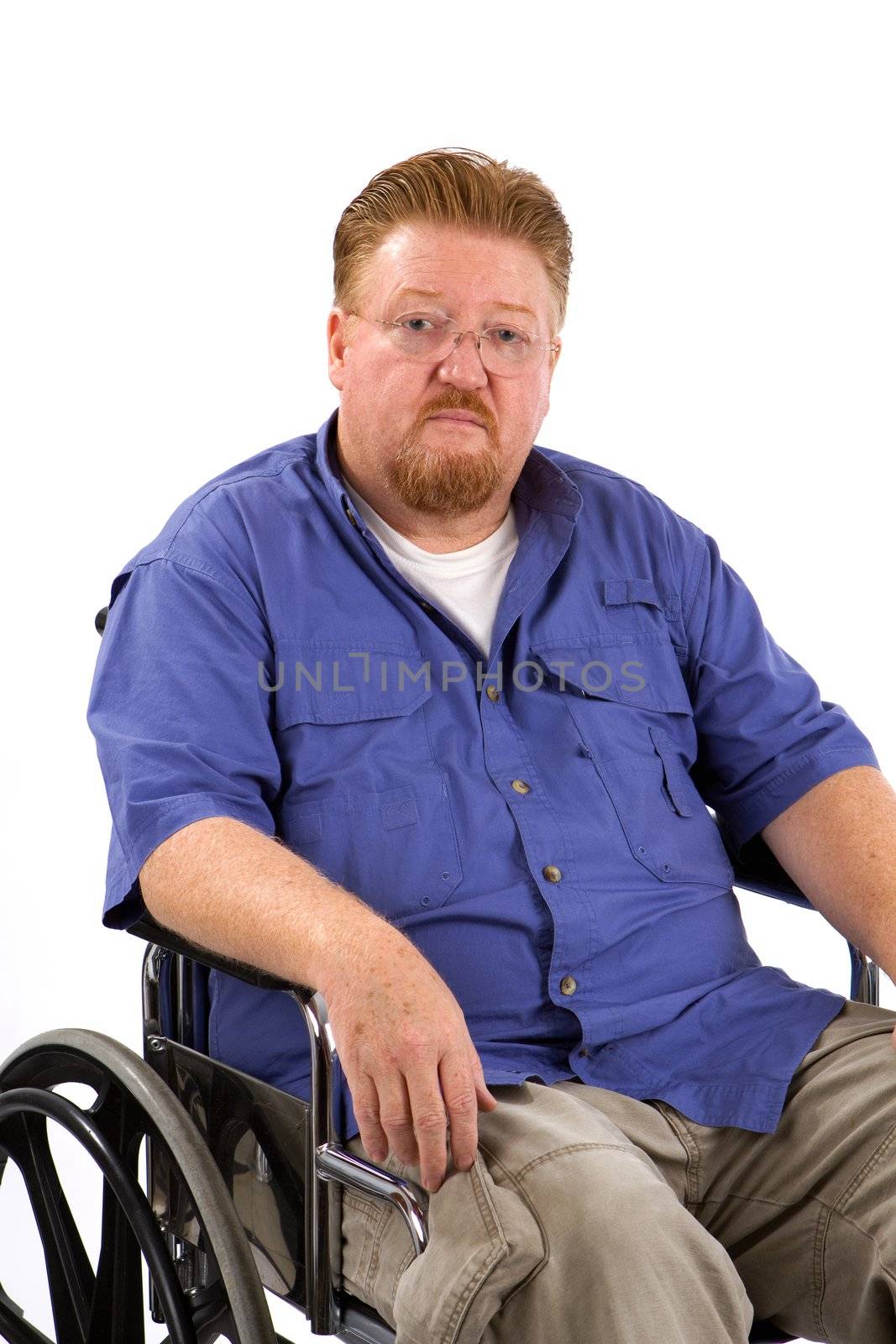 Overweight disabled man sits in a wheelchair with a sad expression on his face.