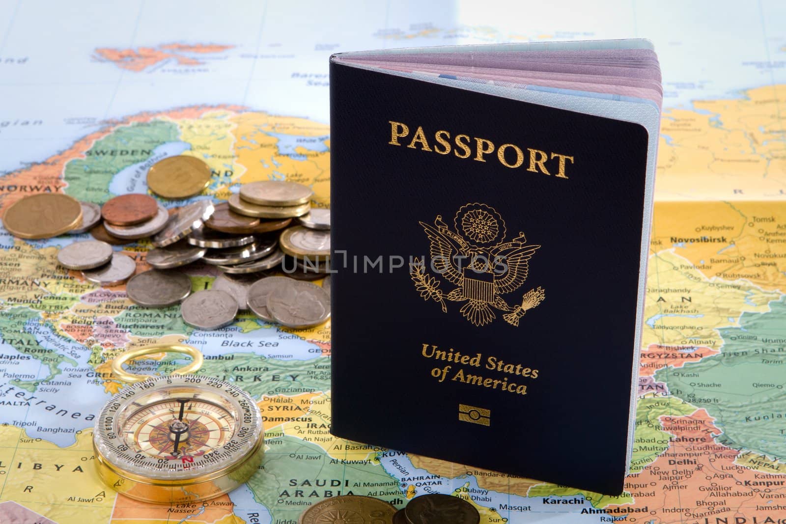 USA passport, compass and foreign coins sit on a map of Europe for an international travel concept.