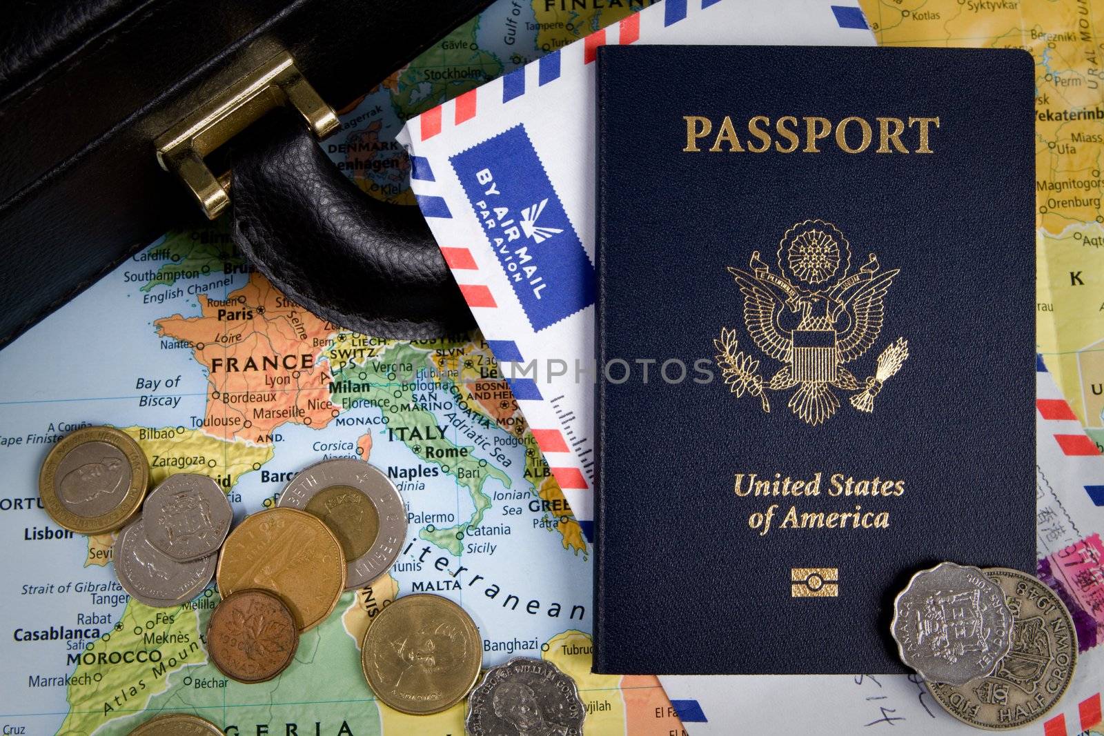 USA passport, foreign coins and briefcase sit on a world map for an international business travel concept.