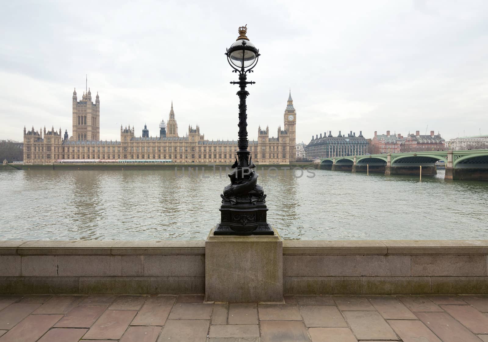 Political center of the United Kingdom - Westminster. View of the Palace of Westminster, which houses Parliament, with the Thames. In the foreground - iron sculpture street light