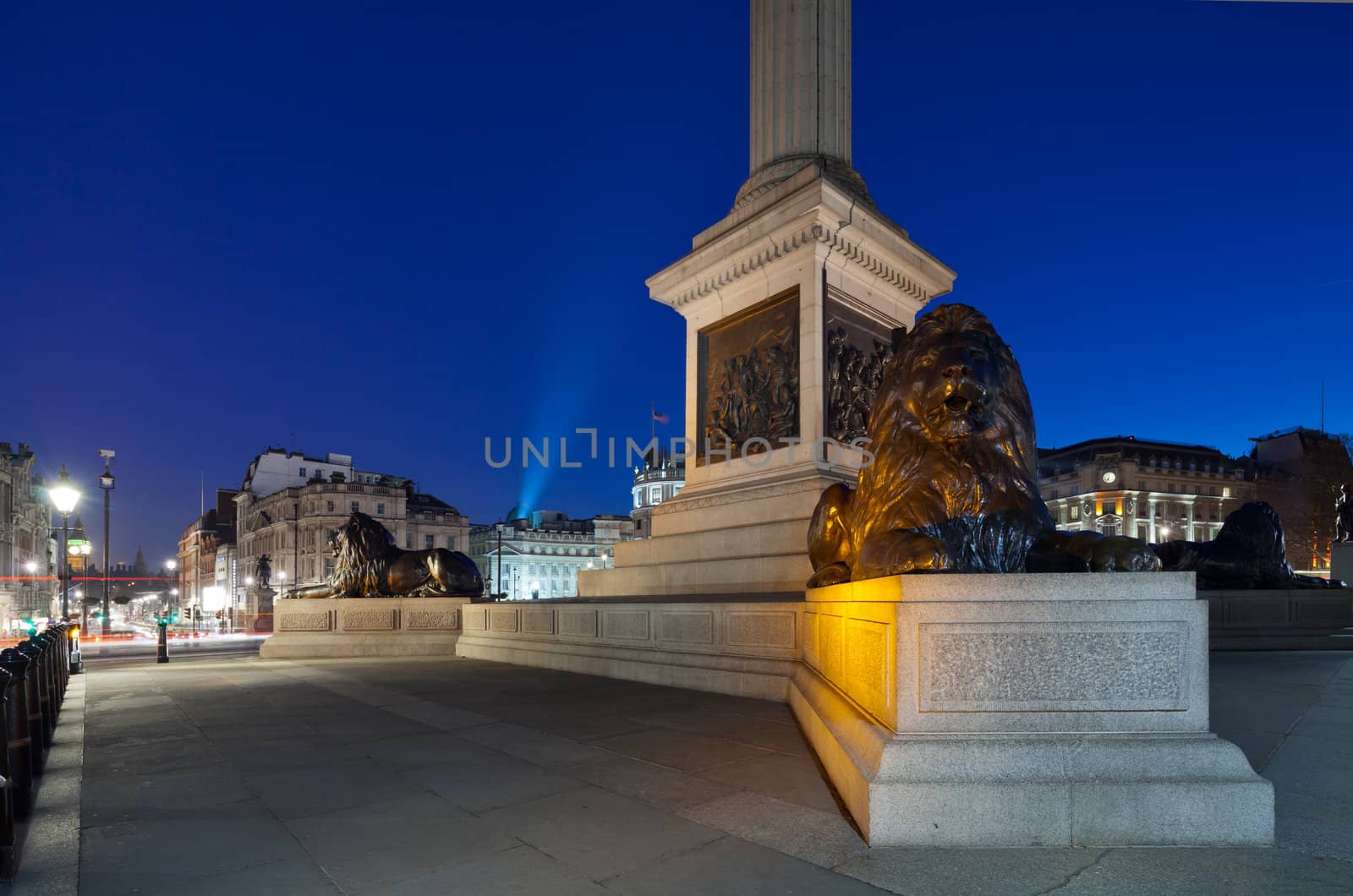 Pedestal Nelson's Column in Trafalgar Square with four lions lying. Shooting in low light. In the background - Big Ben. Cityscape  shot with tilt-shift lens maintaining verticals