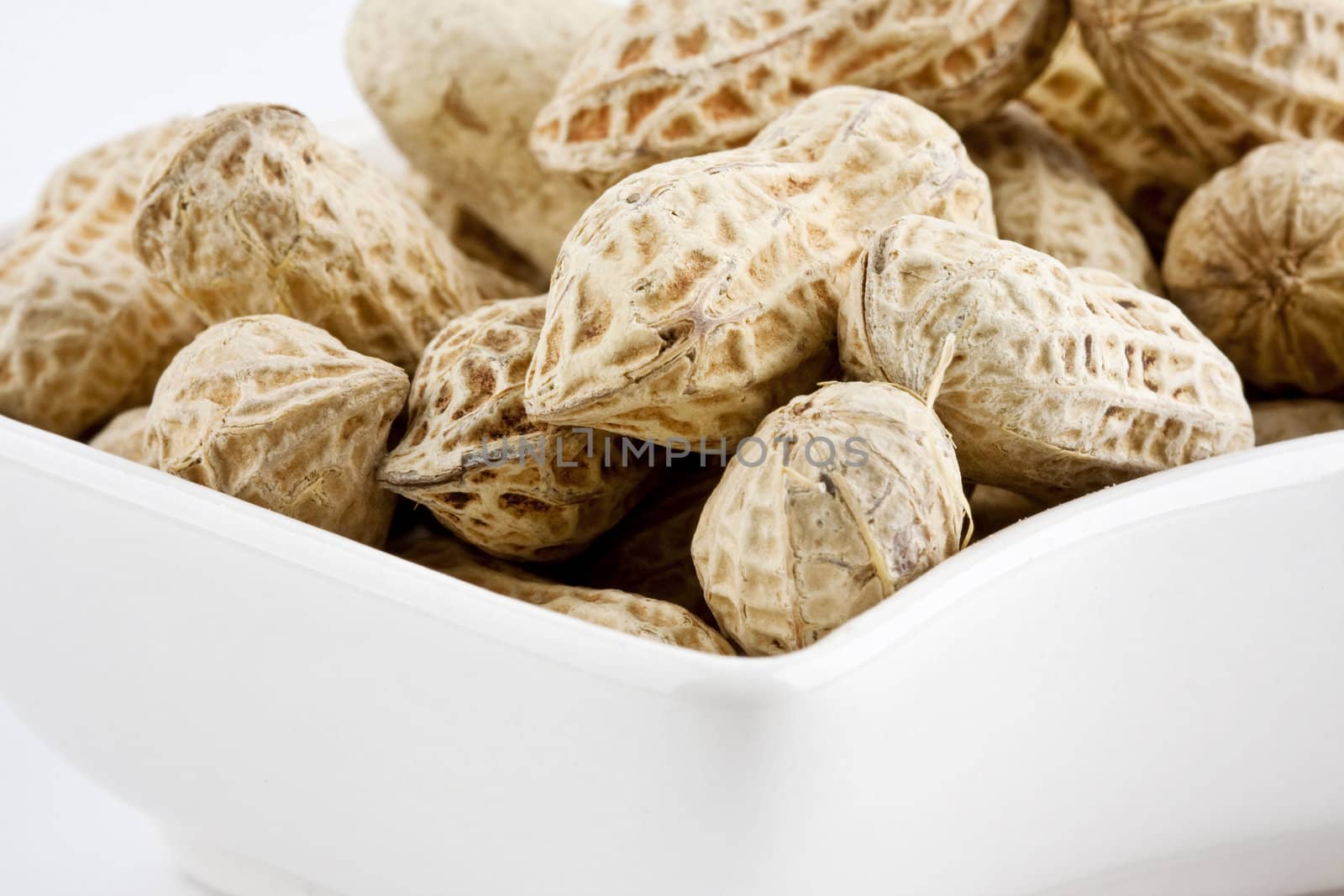 Peanut in shell snack on white plate - shallow DOF focus in the middle