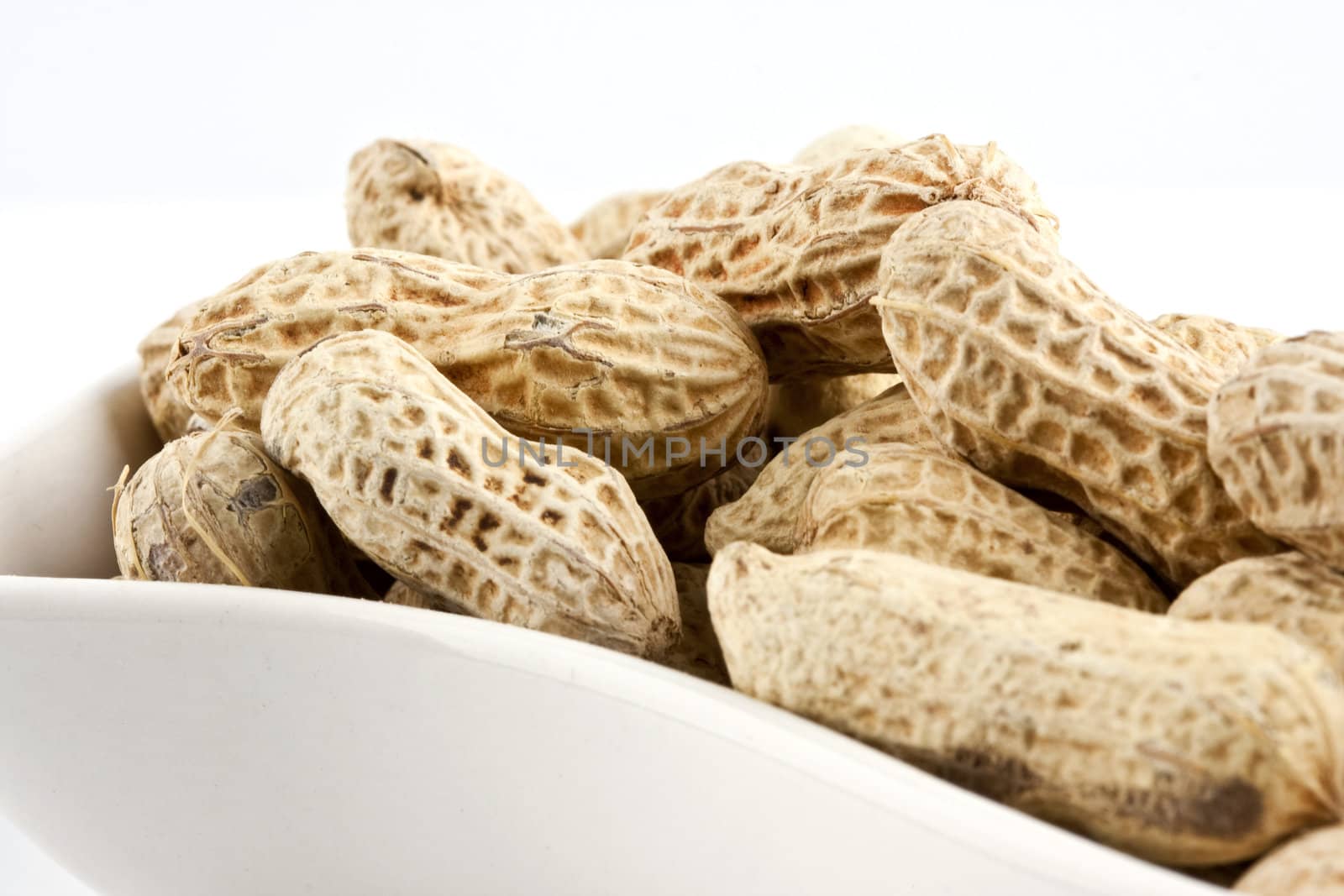 Peanut in shell snack on white plate - shallow DOF focus in the middle