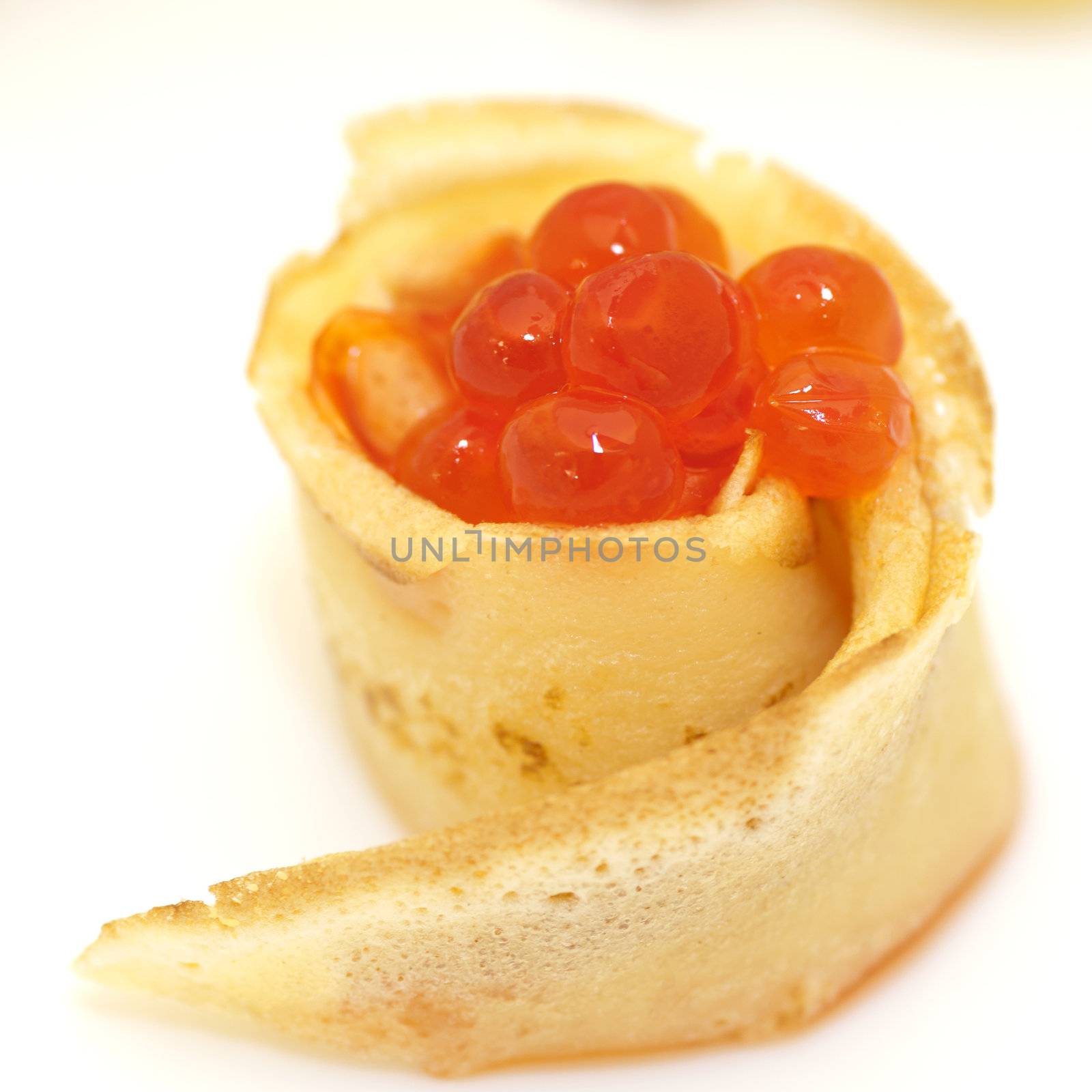 Pancake roll with red caviar close up on white background