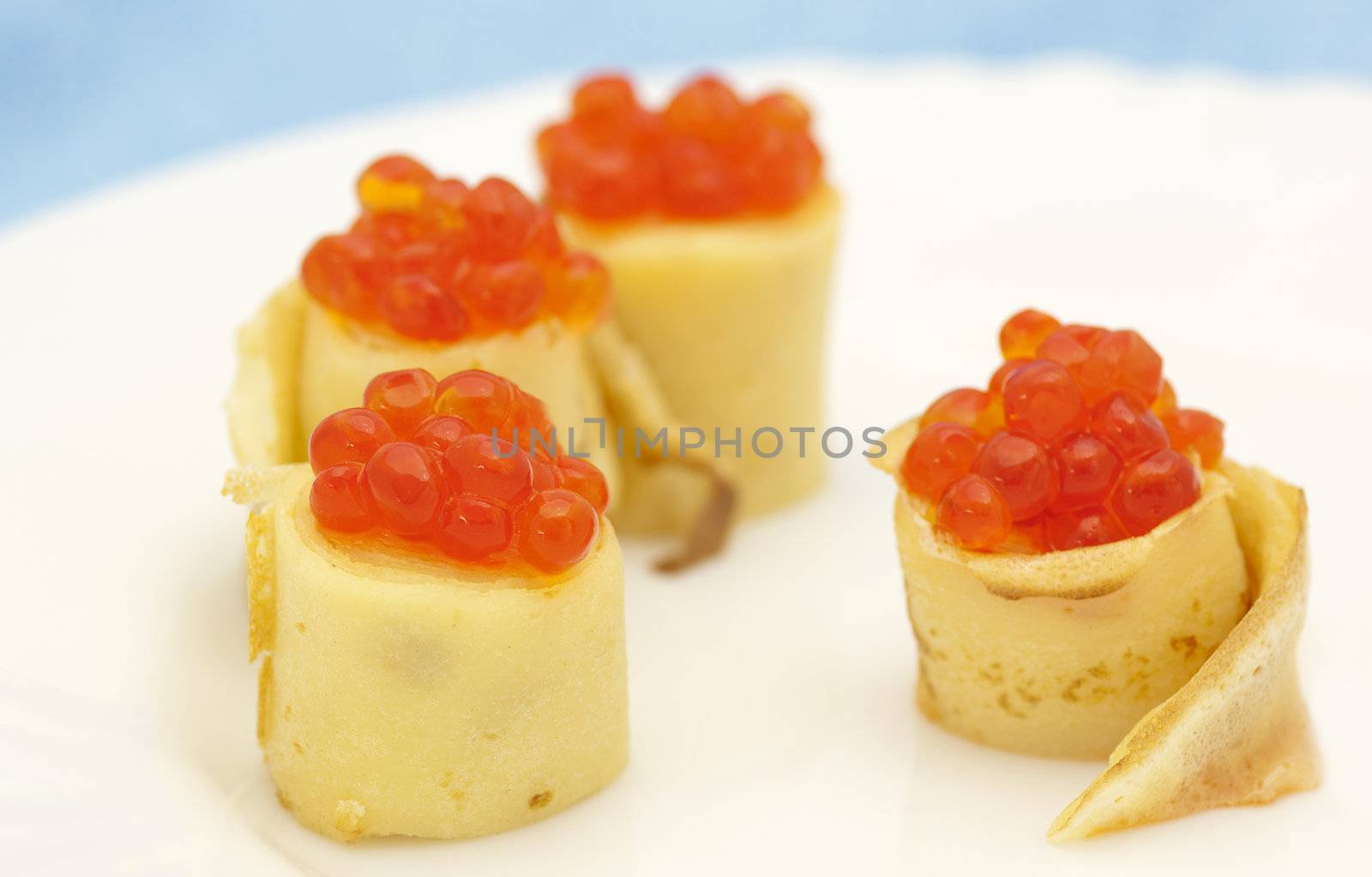 Pancake roll with red caviar close up on white background