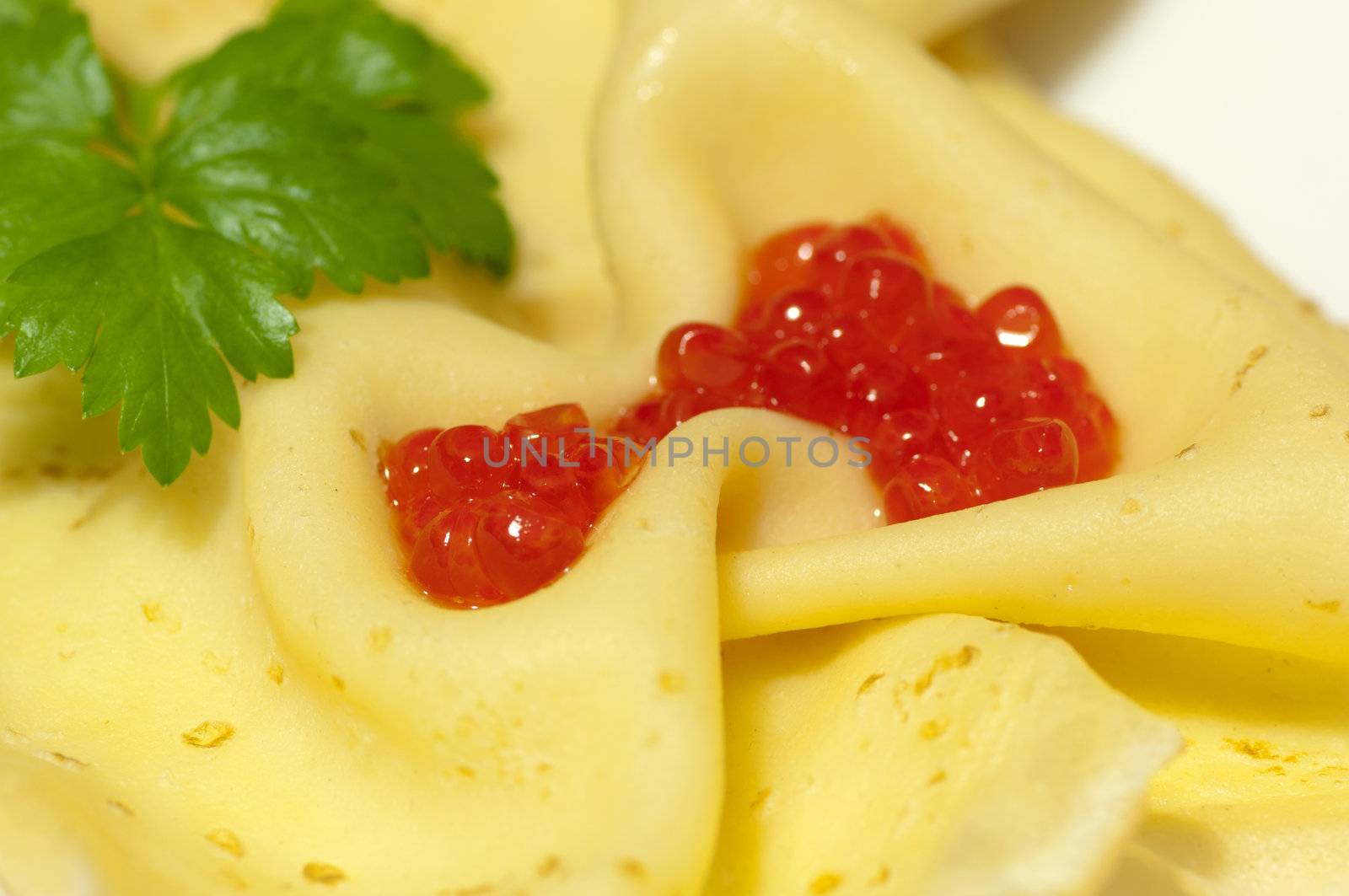 Pancake with red caviar and celery close up