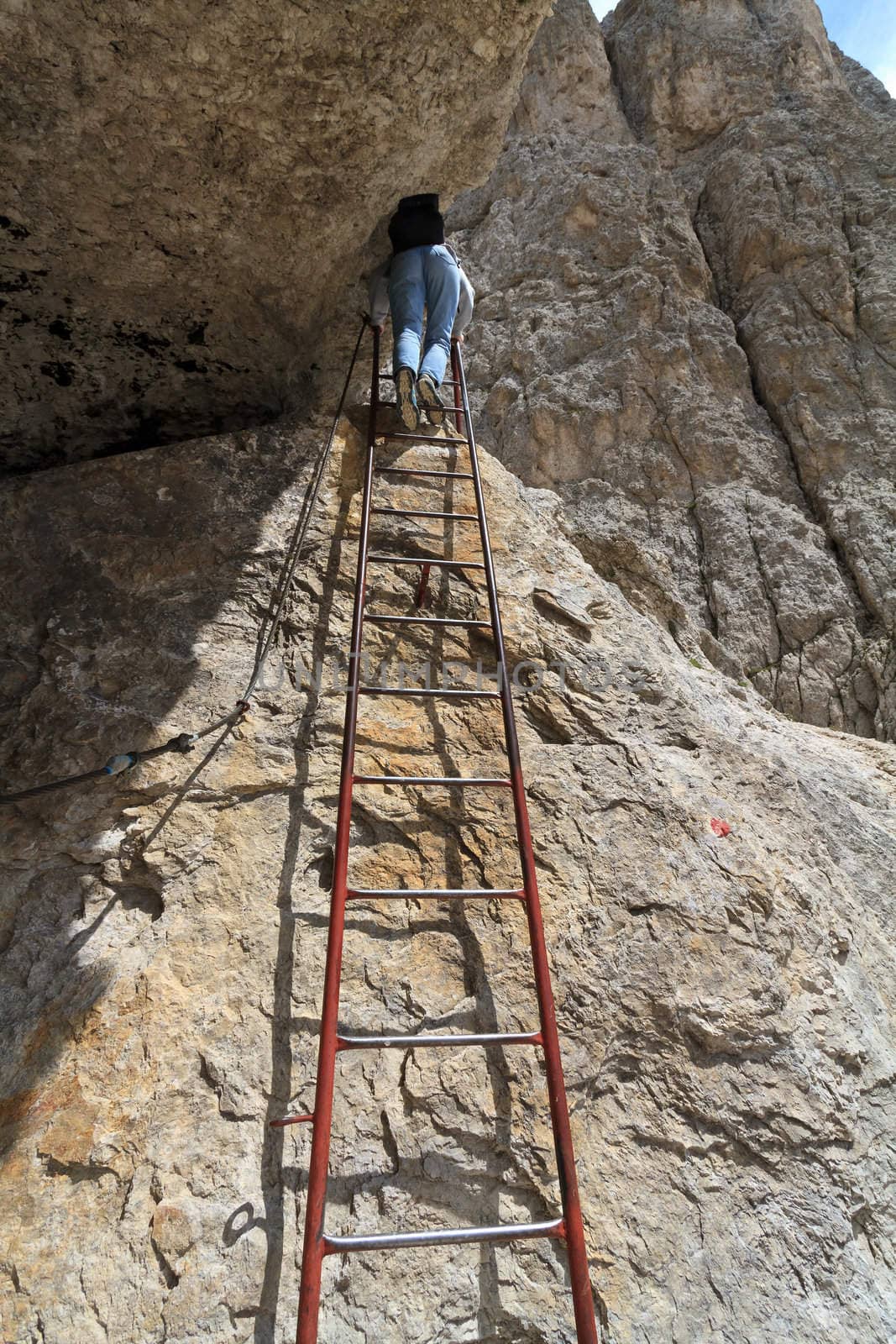 woman is climbing on metal ladder in Italian Dolomites
