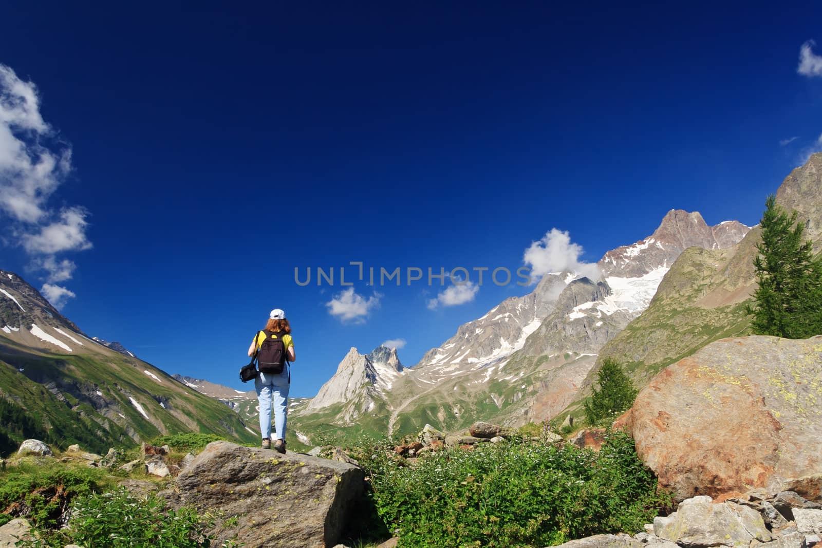 young woman stands on a rocks in Italian Alps