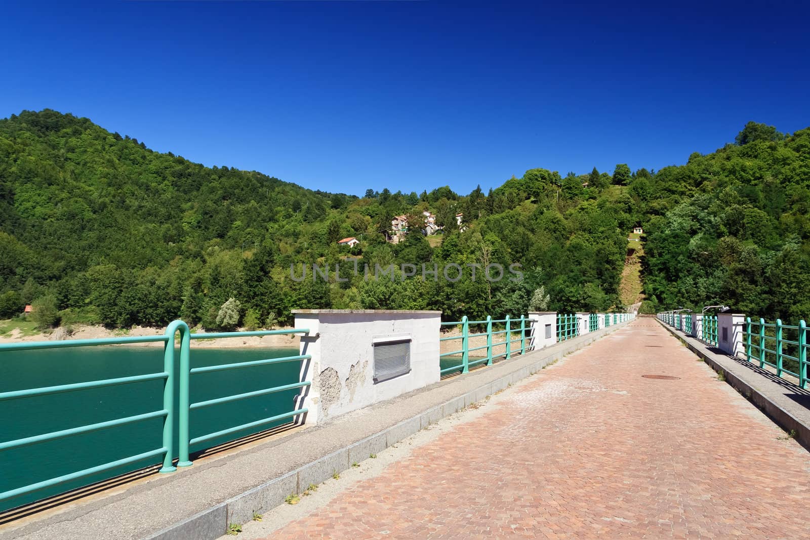 smal pave road across Brugneto lake dam on a sunny day, Liguria, Italy